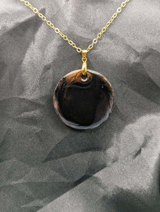 Brown Swirl Resin Circle necklace pendant on a pinch bail and gold plated metal chain.