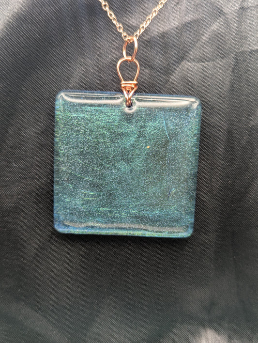 Blue square resin pendant with a color shift background. Resin pendant necklace on a pure copper wire wrapped bail & rose gold colored stainless steel plated metal chain.