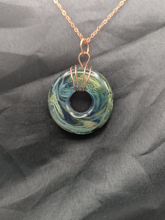 Wire Wrapped Donut Resin Pendant Necklace - Petri Effect with shades of blue, green, & yellow swirls. Resin Necklace on a rose gold colored stainless steel metal chain.