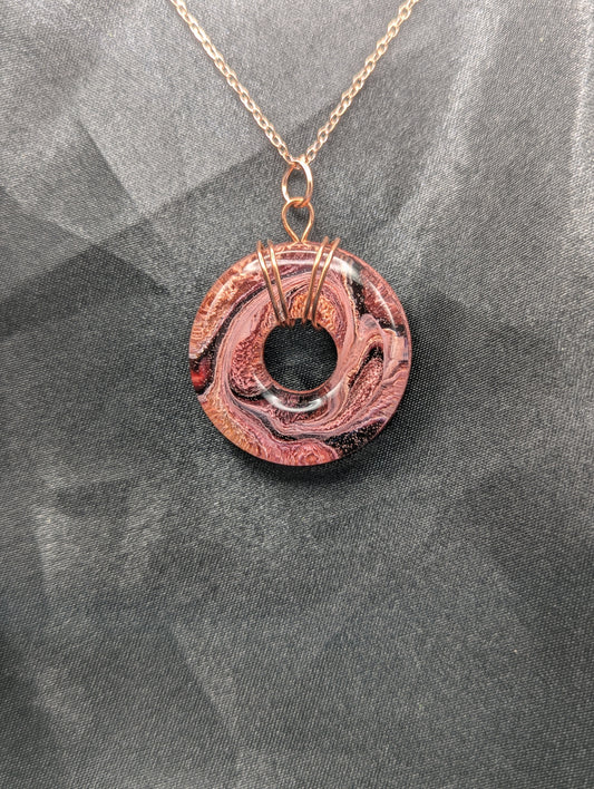 Wire Wrapped Donut Resin Pendant Necklace - Petri Effect with shades of red, pink, & orange swirls. Resin Necklace on a rose gold colored stainless steel plated metal chain.