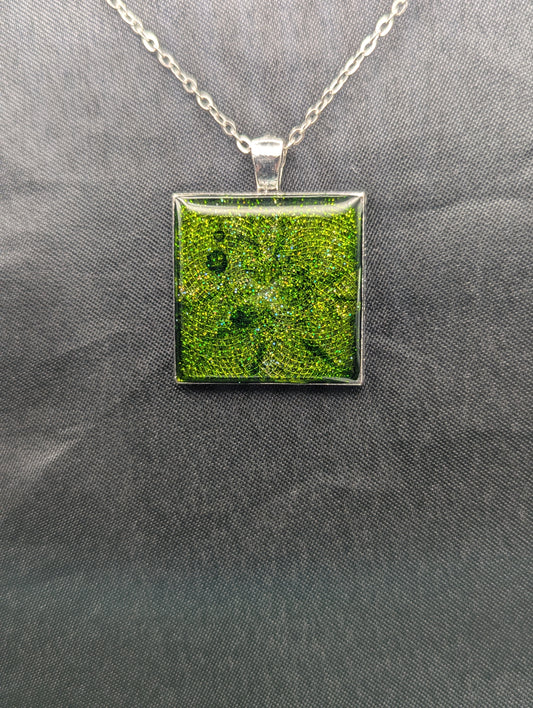 Silver square bezel filled with sparkly green resin. Resin pendant necklace on a stainless steel chain.