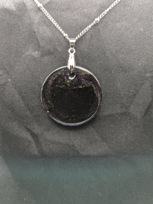 Deep purple circle resin pendant with speckles of green pigment on a silver pinch bail and stainless steel chain