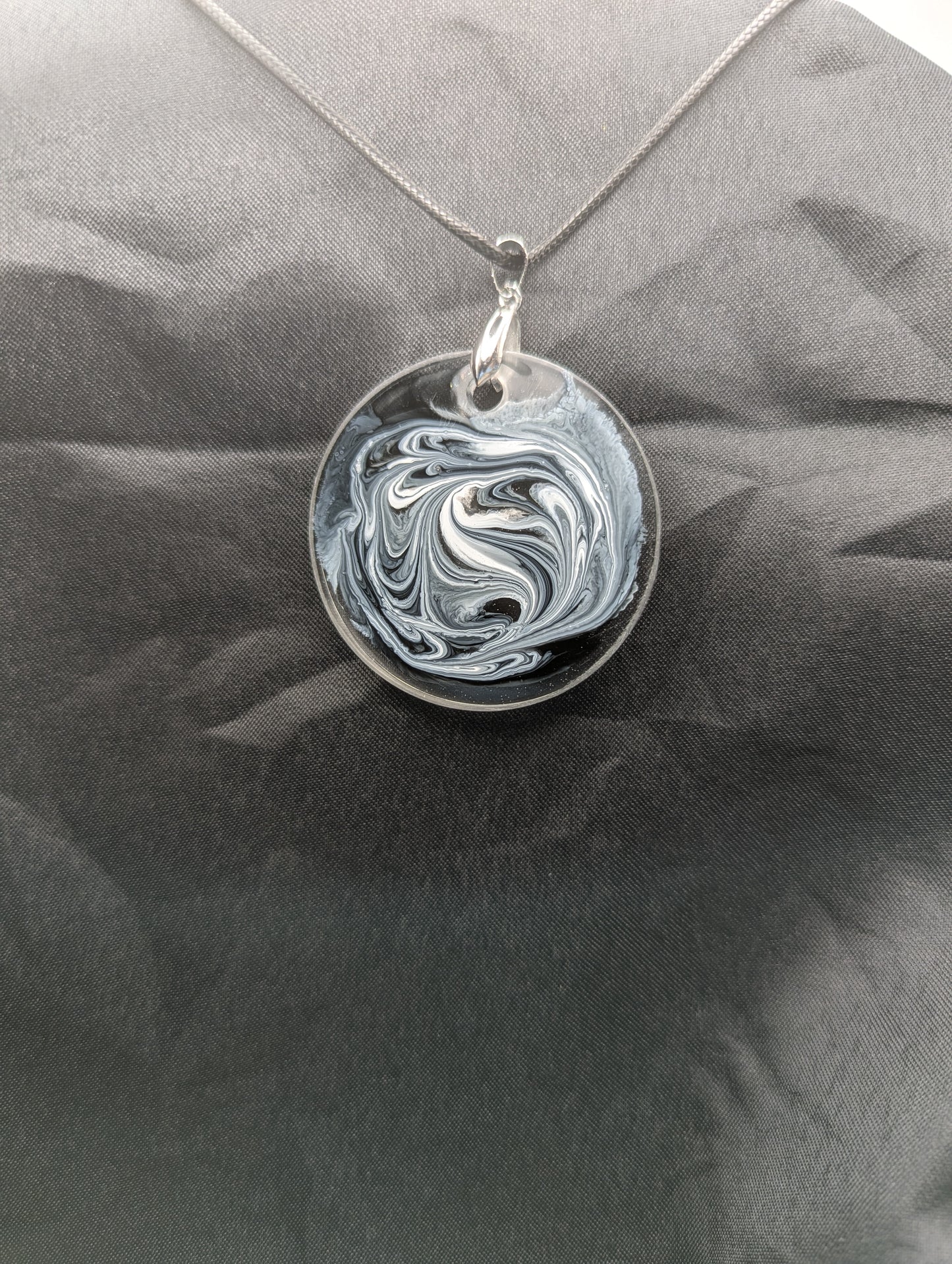 Back view of Black & White Swirl Circle Pendant on a silver pinch bail & waxed cotton cord. Resin Circle Jewelry Pendant with Petri Effect.
