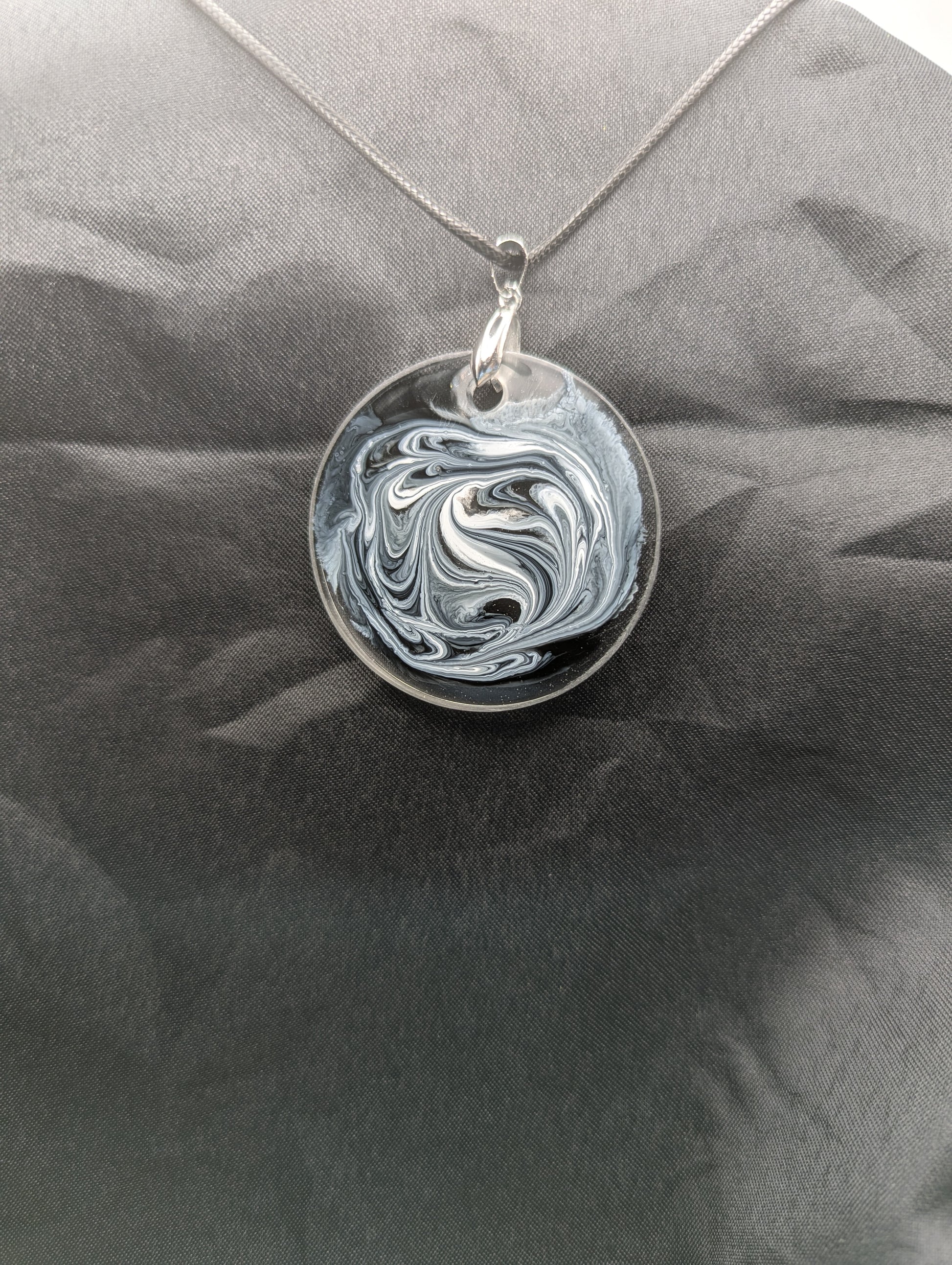 Back view of Black & White Swirl Circle Pendant on a silver pinch bail & waxed cotton cord. Resin Circle Jewelry Pendant with Petri Effect.