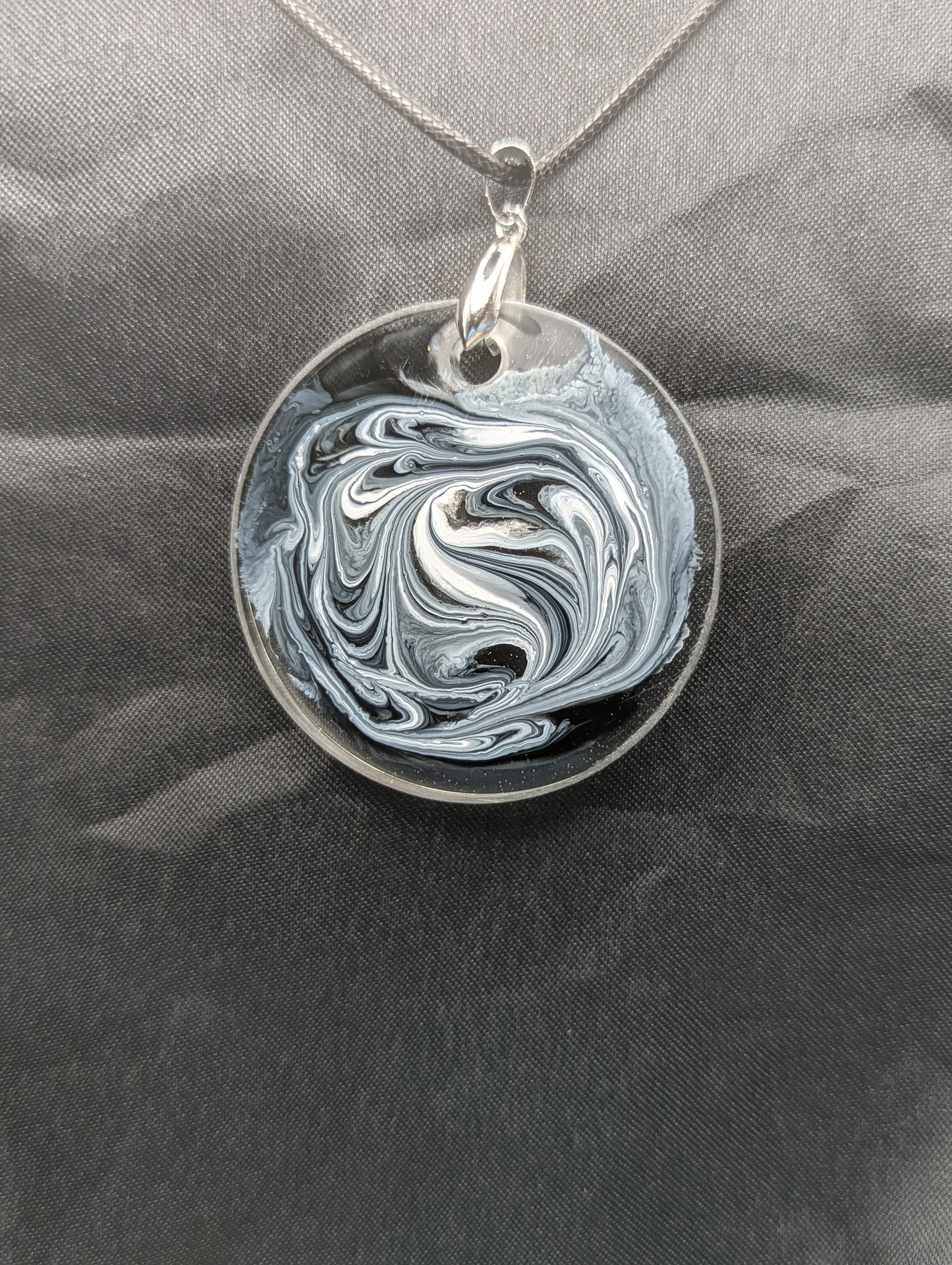 Back view of Black & White Swirl Circle Pendant on a silver pinch bail & waxed cotton cord. Resin Circle Jewelry Pendant with Petri Effect.