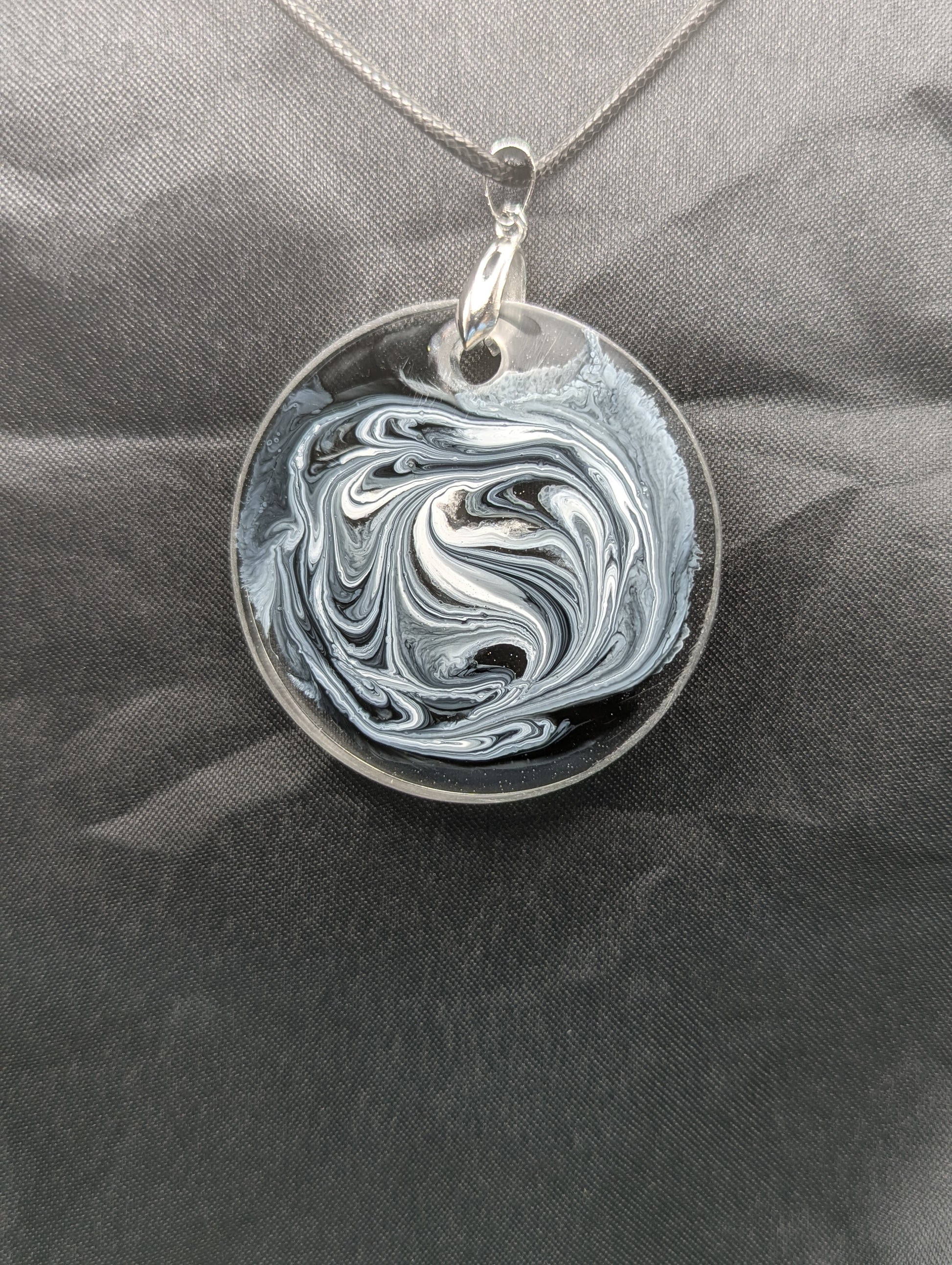 Back view of Black & White Swirl Circle Pendant on a silver pinch bail & waxed cotton cord. Resin Circle Jewelry Pendant with Petri Effect.