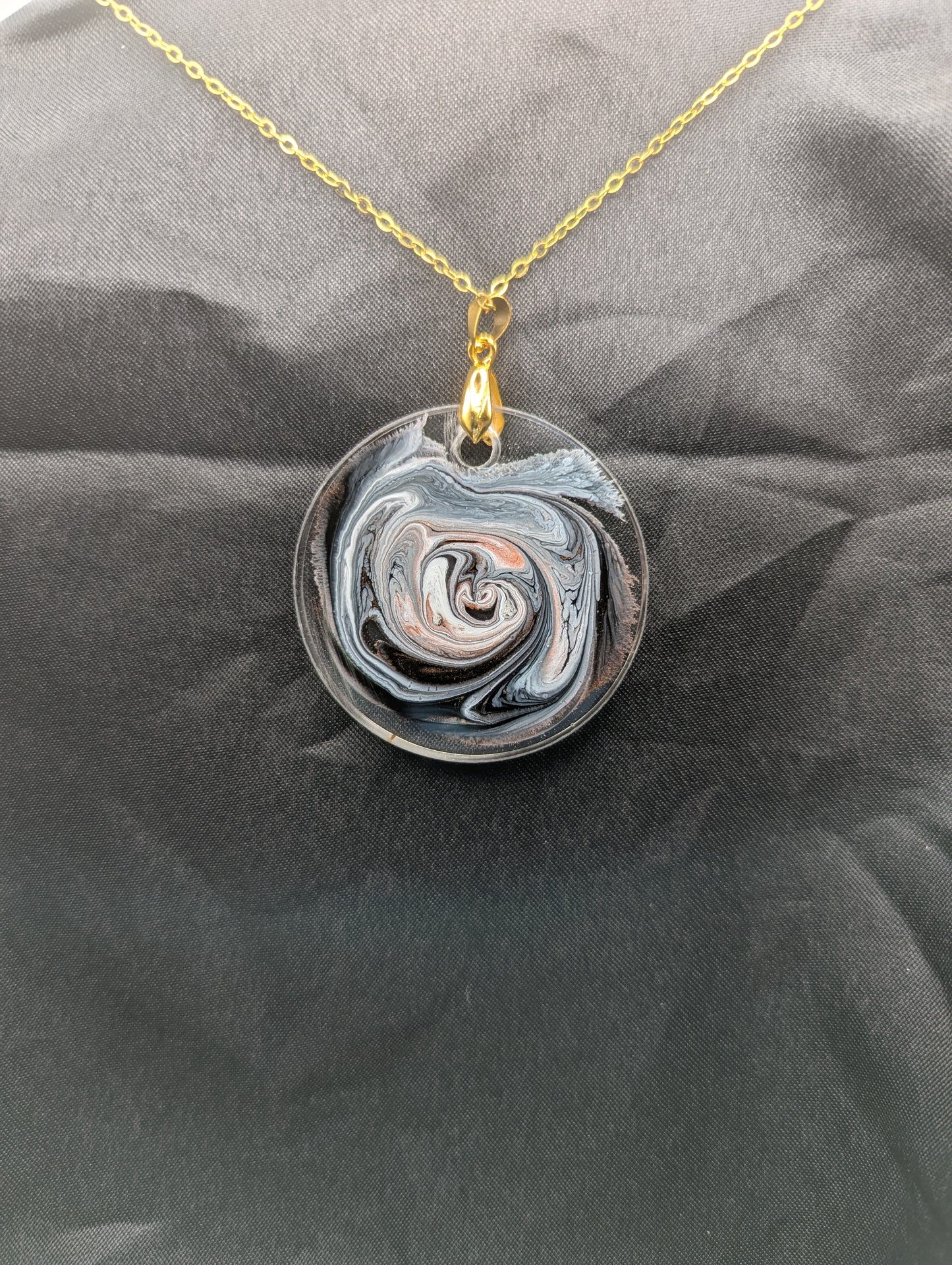 Back view of Brown Swirl Circle Pendant with shades of brown, red, & black on a gold pinch bail & golden stainless steel chain. Resin Circle Jewelry Pendant with Petri Effect.
