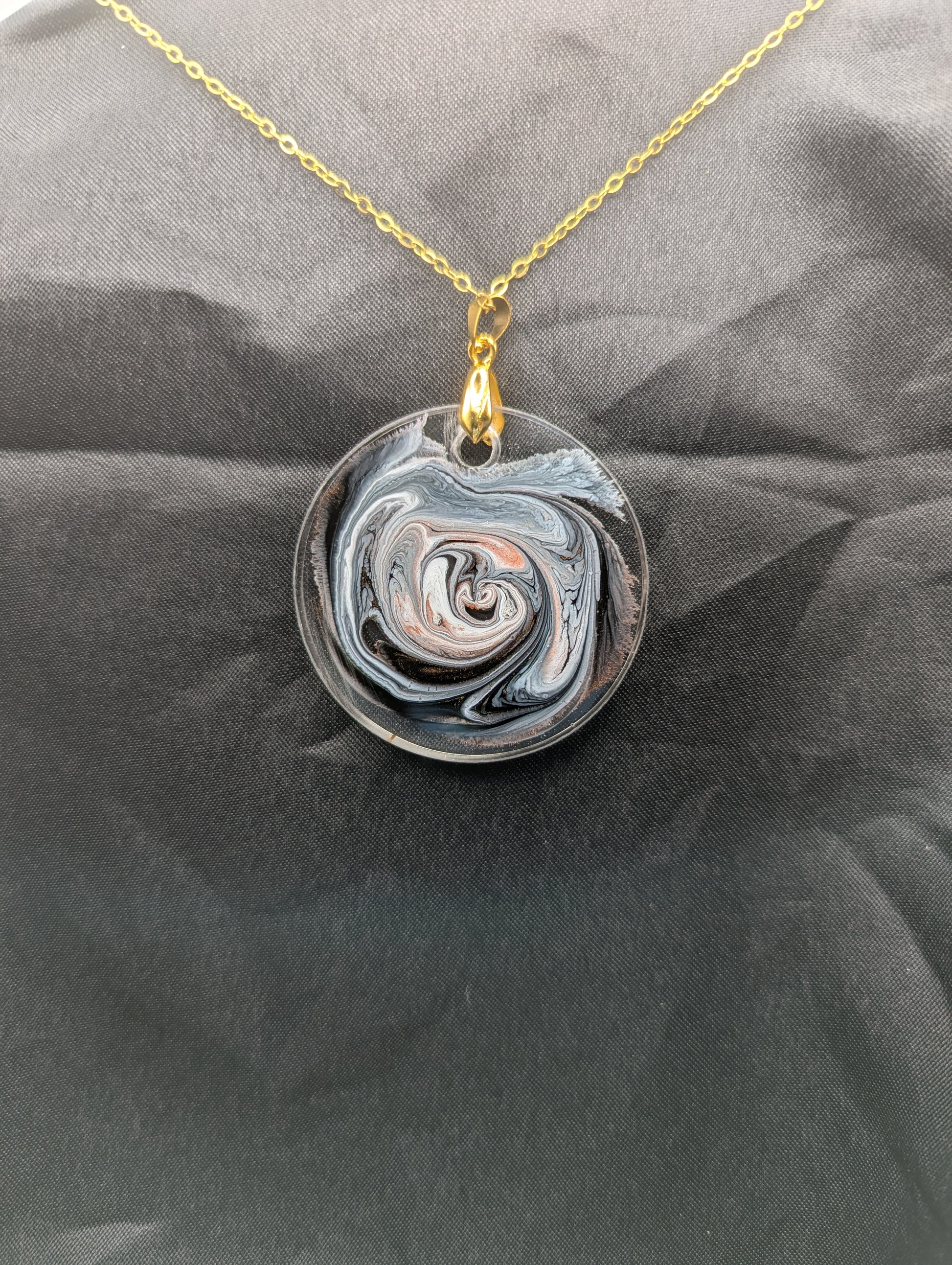 Back view of Brown Swirl Circle Pendant with shades of brown, red, & black on a gold pinch bail & golden stainless steel chain. Resin Circle Jewelry Pendant with Petri Effect.
