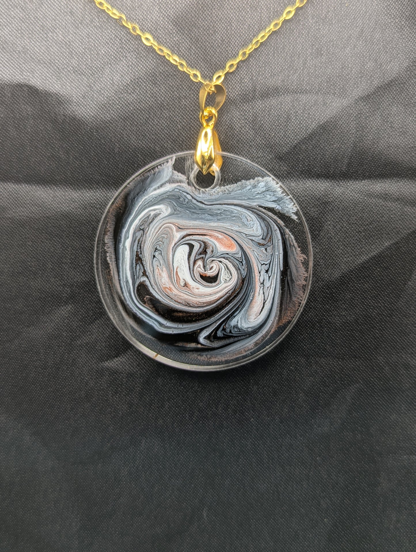 Back view of Brown Swirl Circle Pendant with shades of brown, red, & black on a gold pinch bail & golden stainless steel chain. Resin Circle Jewelry Pendant with Petri Effect.