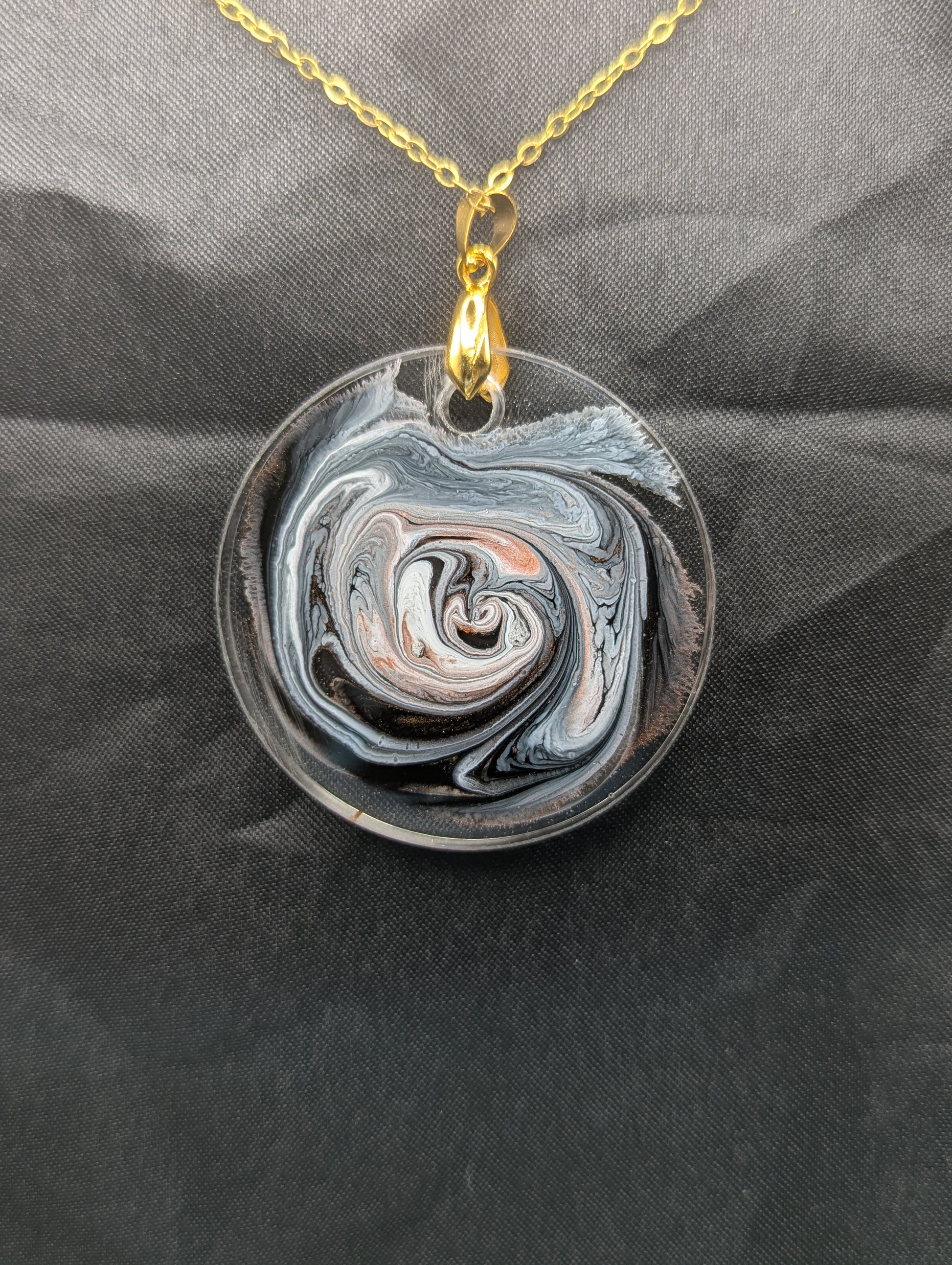 Back view of Brown Swirl Circle Pendant with shades of brown, red, & black on a gold pinch bail & golden stainless steel chain. Resin Circle Jewelry Pendant with Petri Effect.