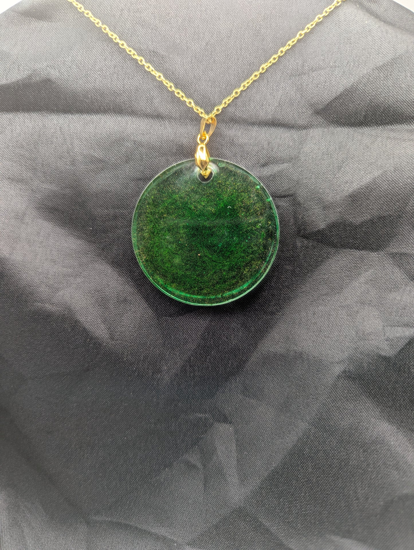 Back view of Green Resin Circle Pendant Necklace with swirls of light orange on a gold pinch bail & gold plated metal chain.
