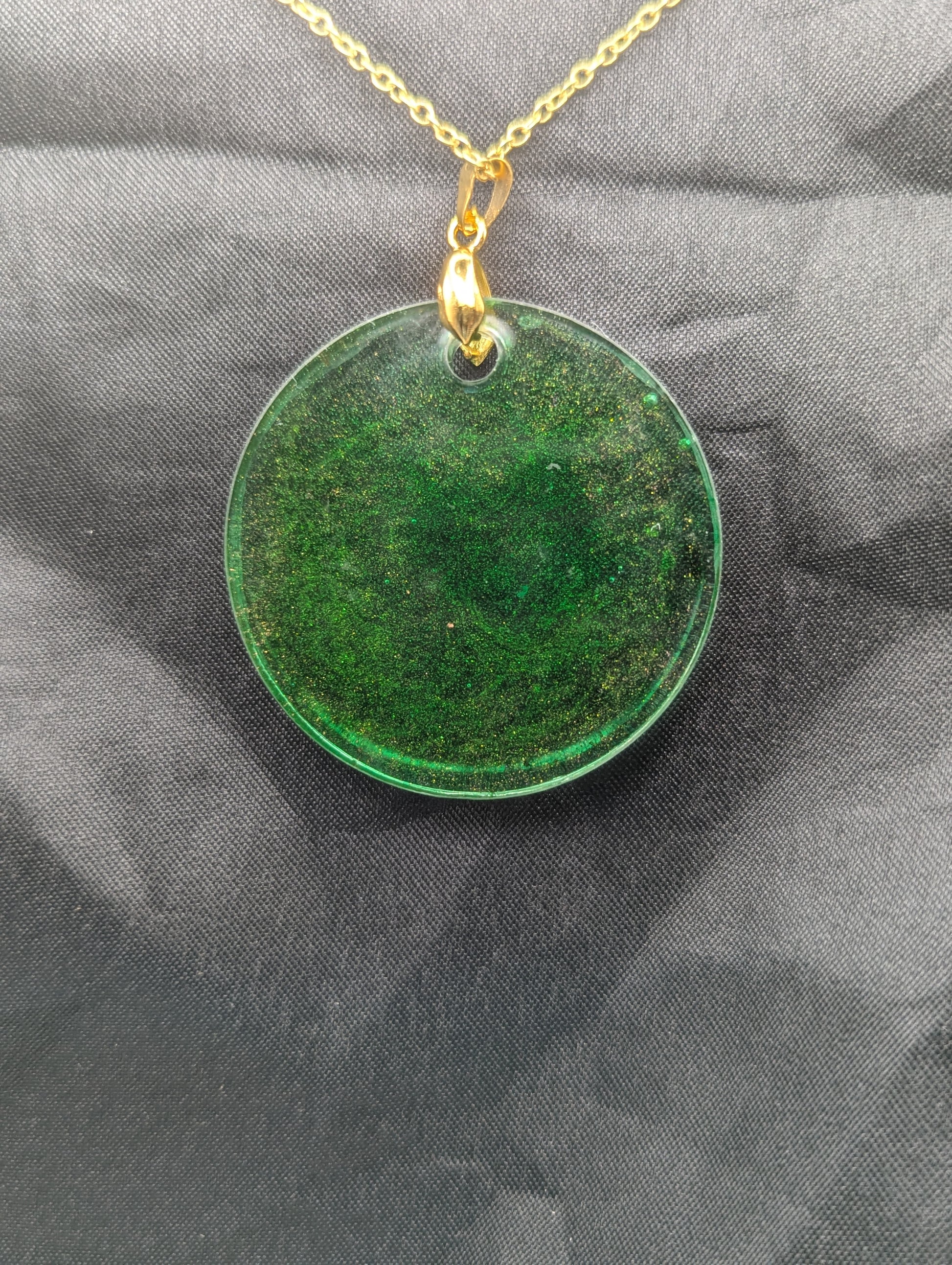 Back view of Green Resin Circle Pendant Necklace with swirls of light orange on a gold pinch bail & gold plated metal chain.