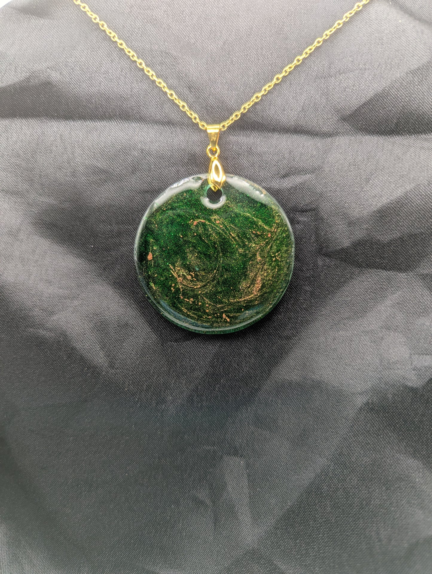 Green Resin Circle Pendant Necklace with swirls of light orange on a gold pinch bail & gold plated metal chain.