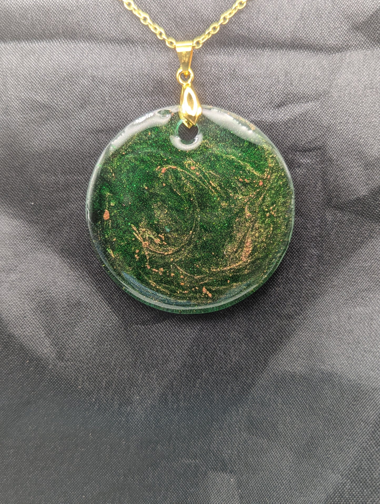 Green Resin Circle Pendant Necklace with swirls of light orange on a gold pinch bail & gold plated metal chain.