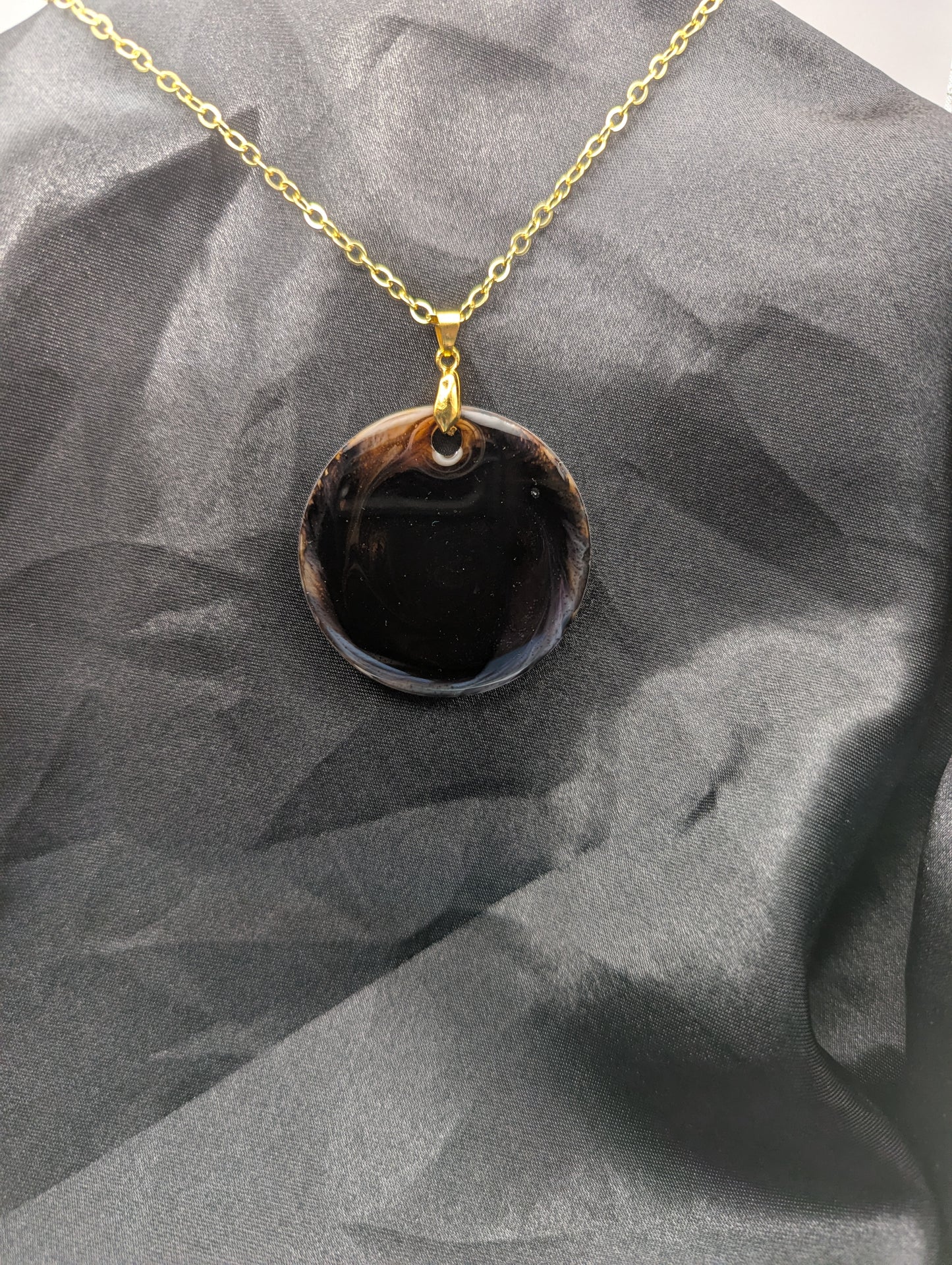 Brown Swirl Resin Circle necklace pendant on a pinch bail and gold plated metal chain.