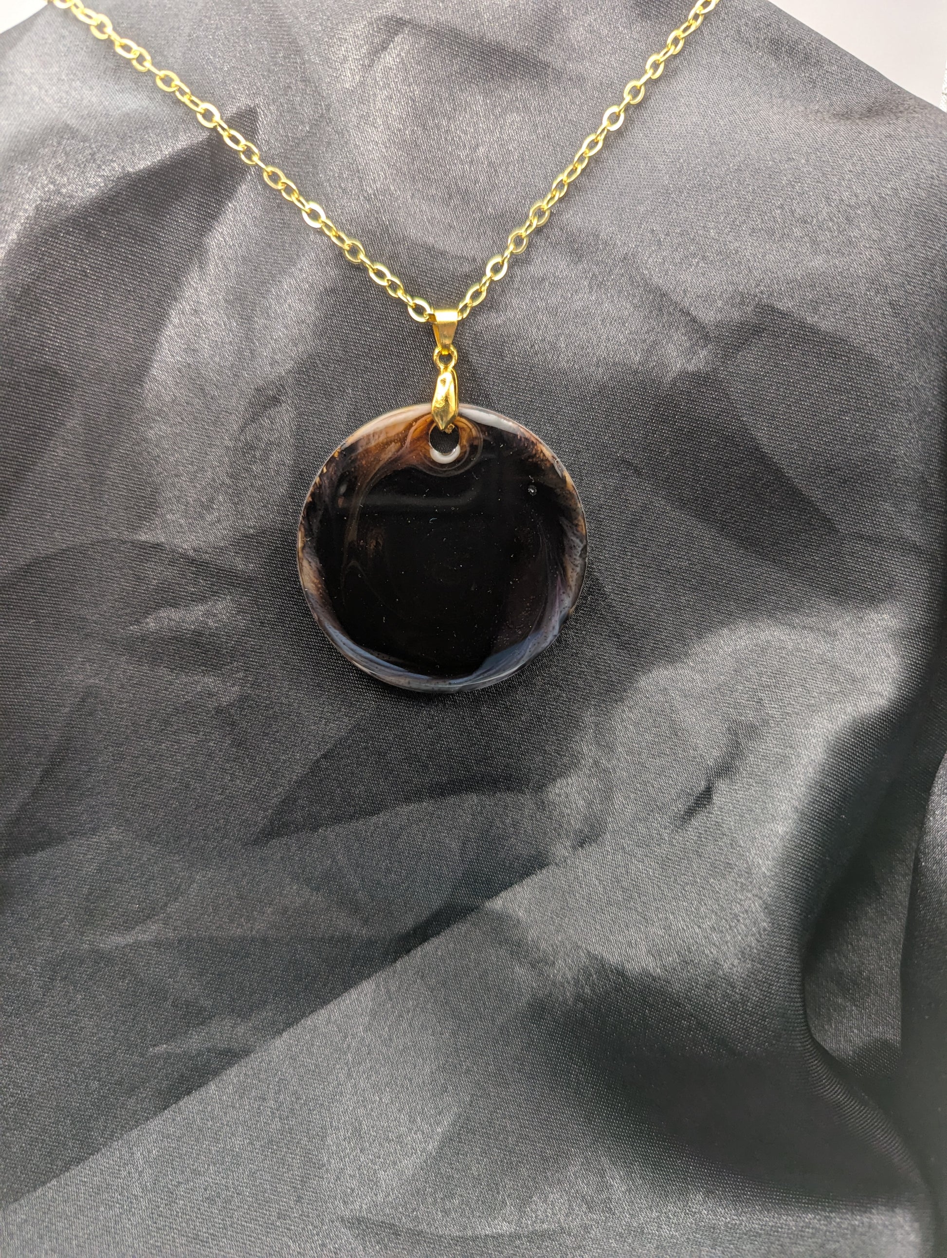Brown Swirl Resin Circle necklace pendant on a pinch bail and gold plated metal chain.