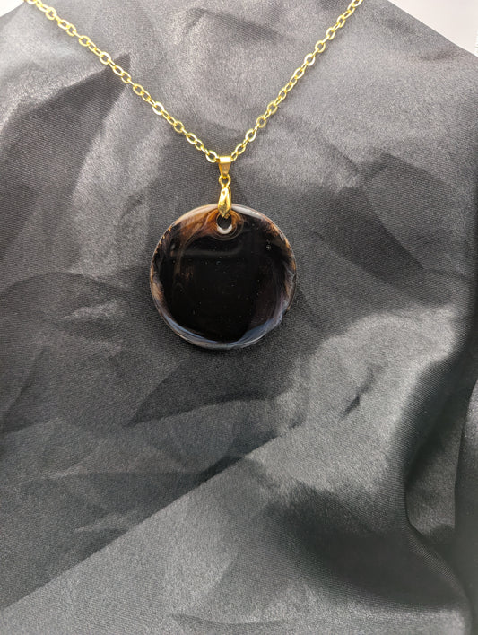 Brown Swirl Resin Circle necklace pendant on a pinch bail and gold plated metal chain.