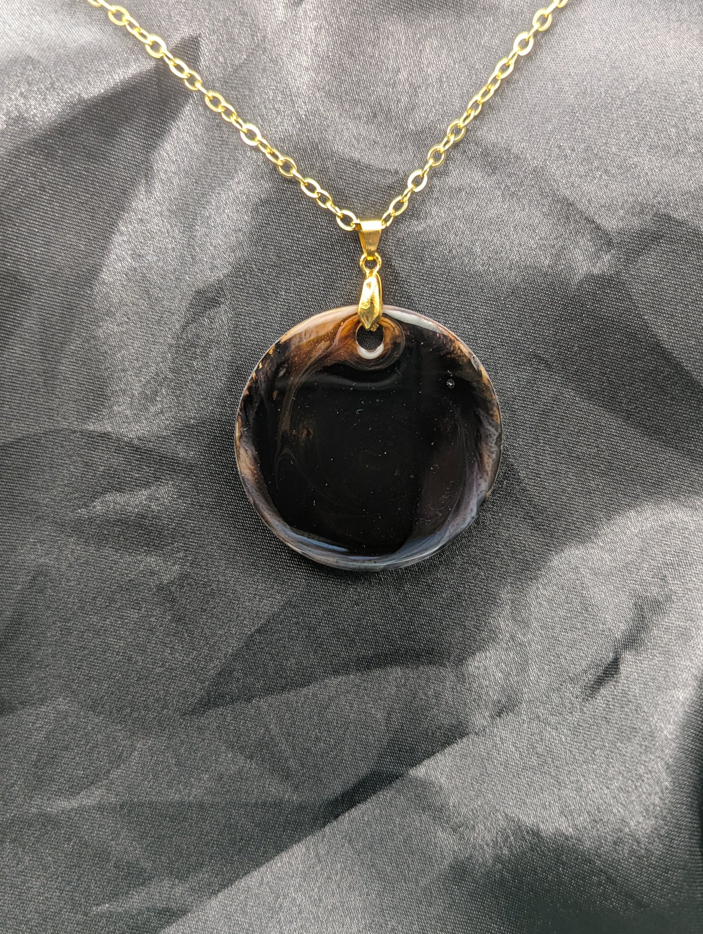 Brown Swirl Resin Circle necklace pendant on a pinch bail and gold plated metal chain.