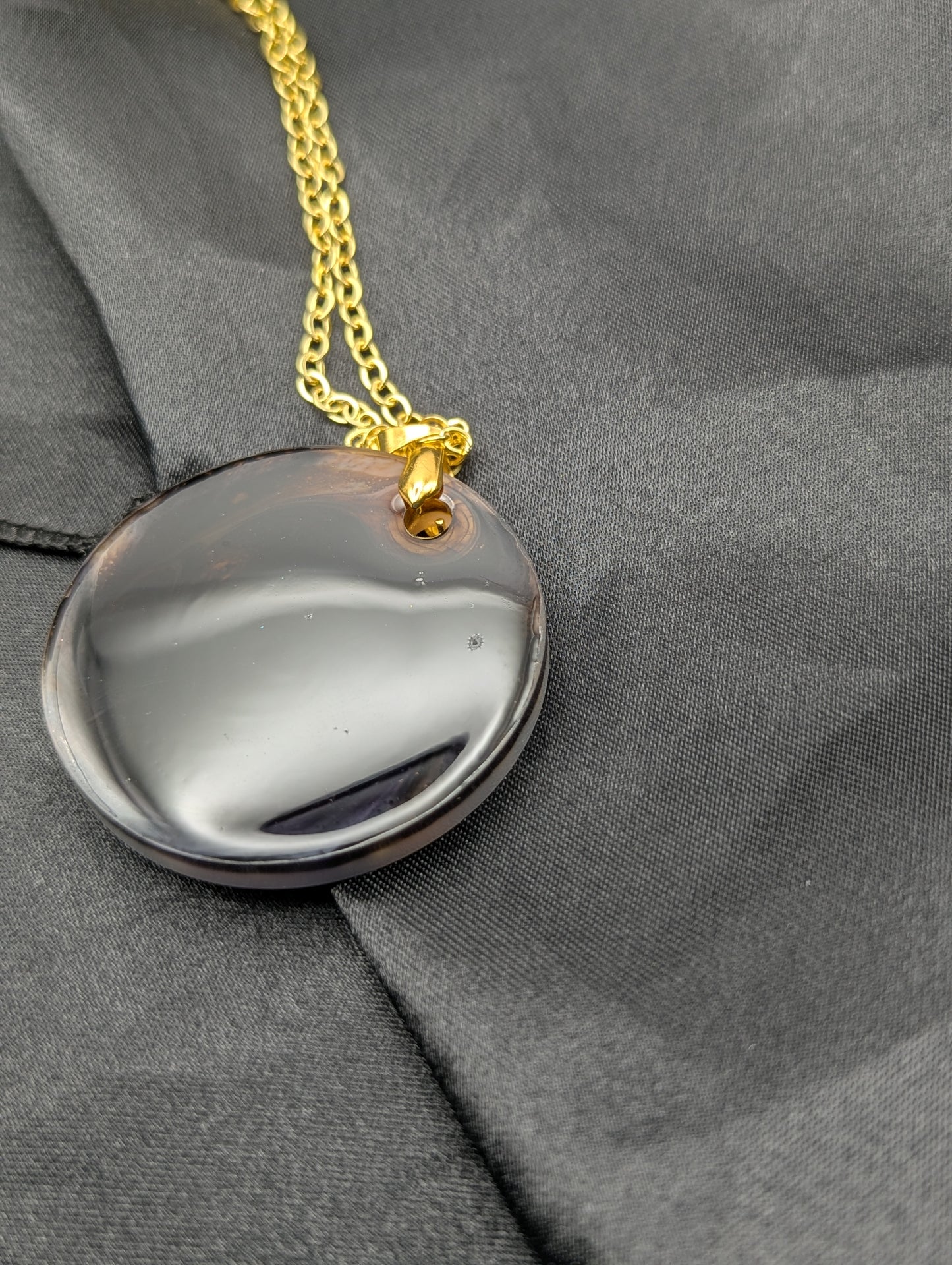 Brown Swirl Resin Circle necklace pendant on a pinch bail and gold plated metal chain.