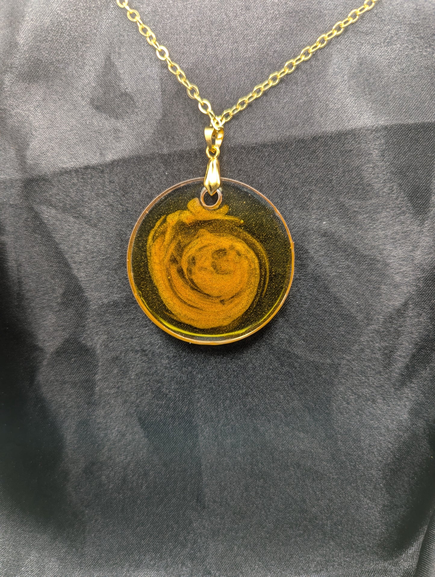 Back view of Yellow & orange swirl circle resin pendant on a gold pinch bail & gold plated metal chain.