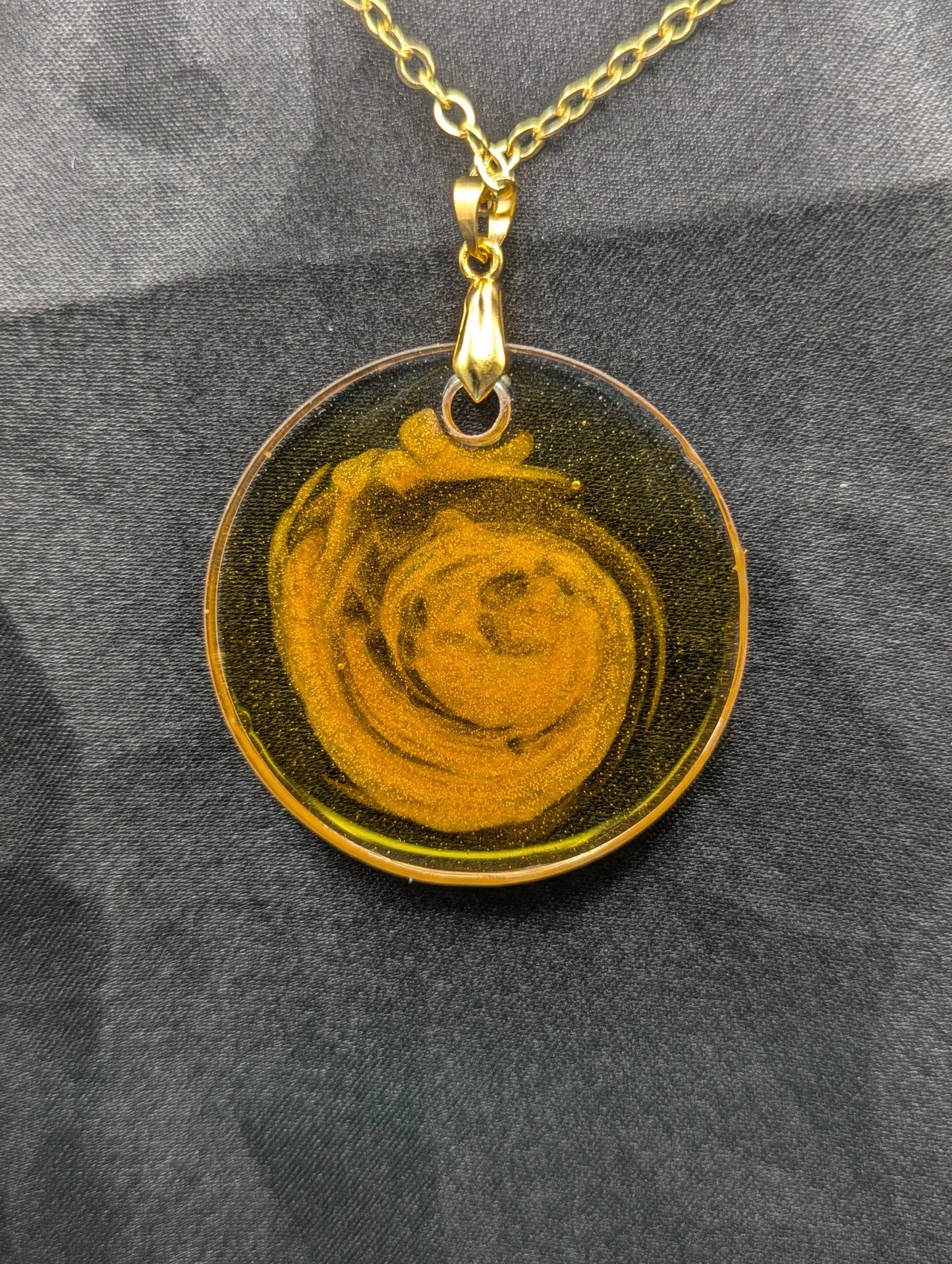 Back view of Yellow & orange swirl circle resin pendant on a gold pinch bail & gold plated metal chain.