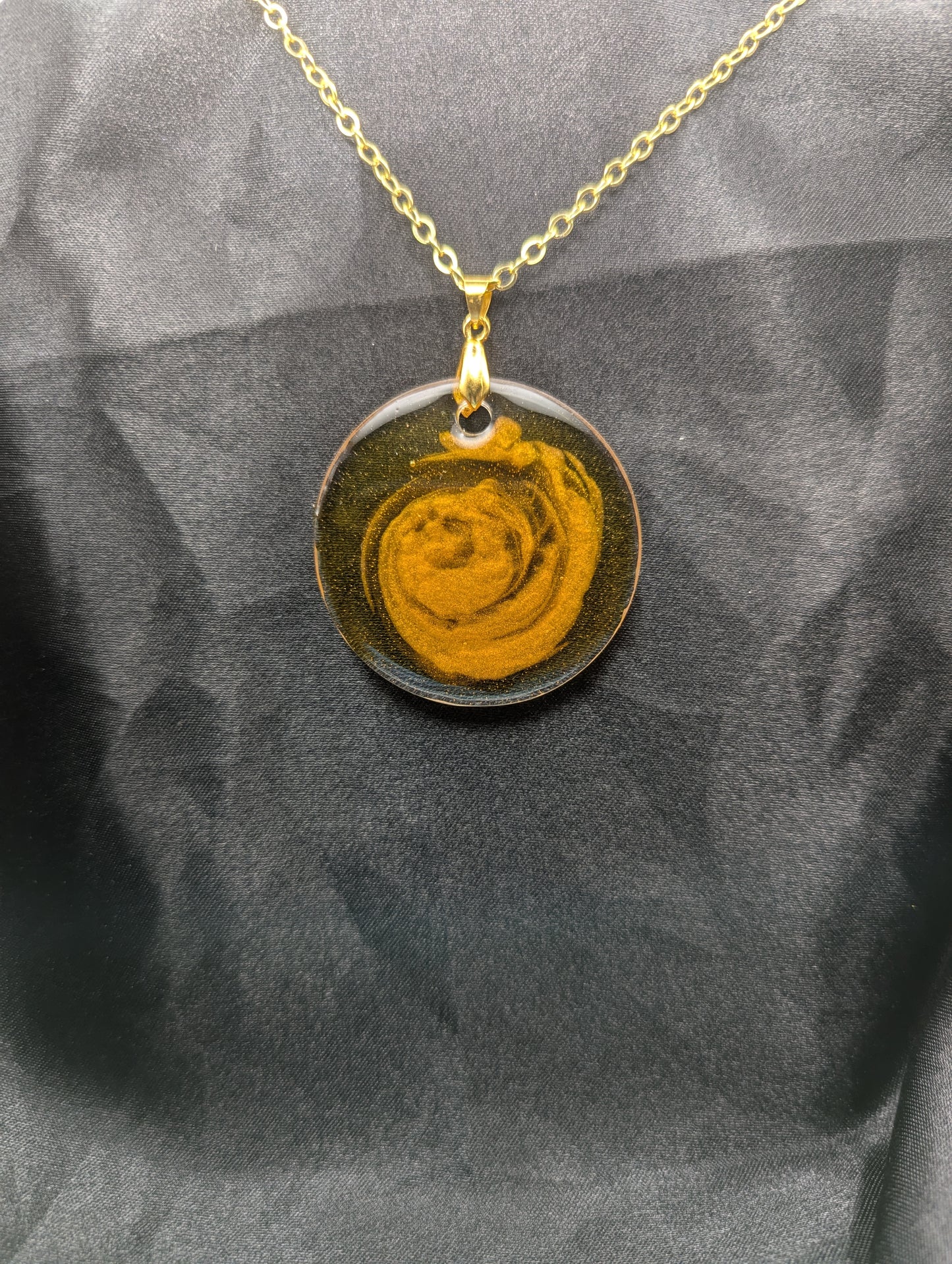 Yellow & orange swirl circle resin pendant on a gold pinch bail & gold plated metal chain.
