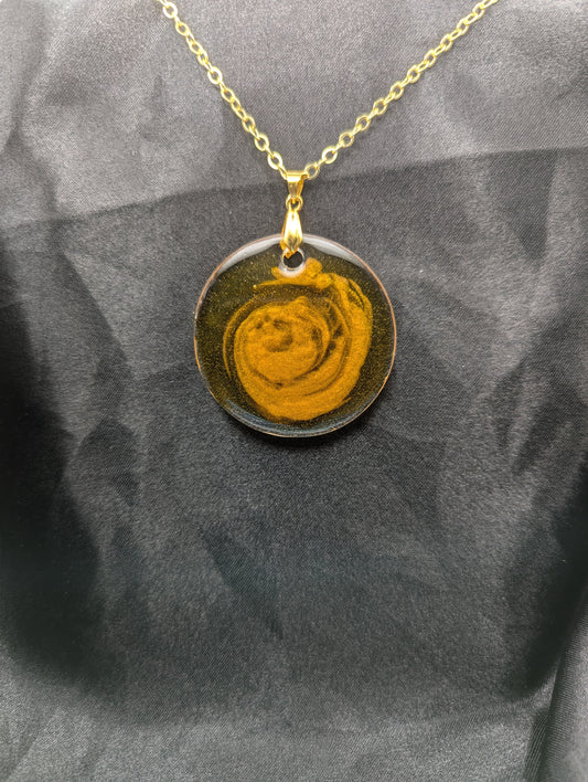 Yellow & orange swirl circle resin pendant on a gold pinch bail & gold plated metal chain.