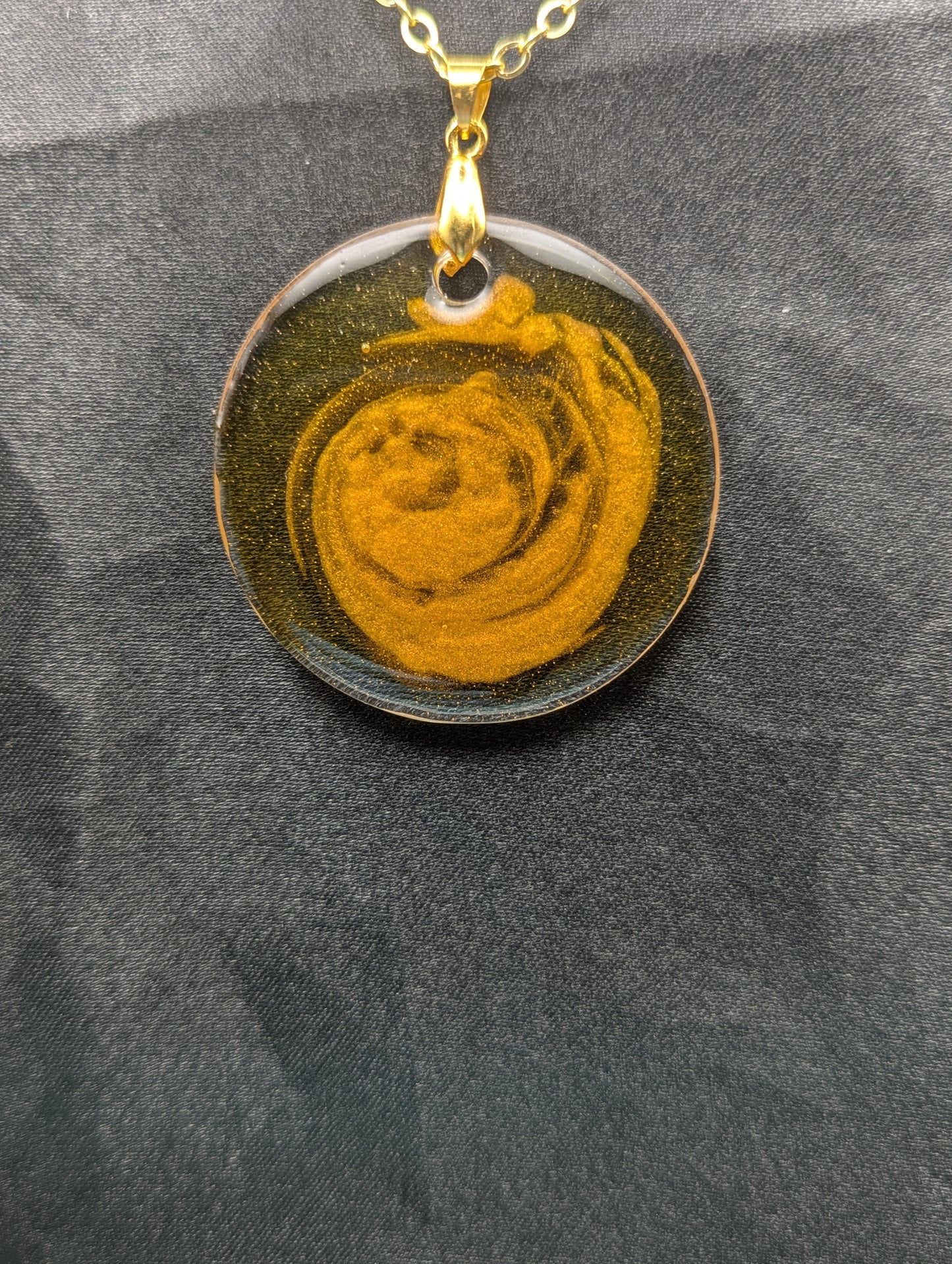 Yellow & orange swirl circle resin pendant on a gold pinch bail & gold plated metal chain.