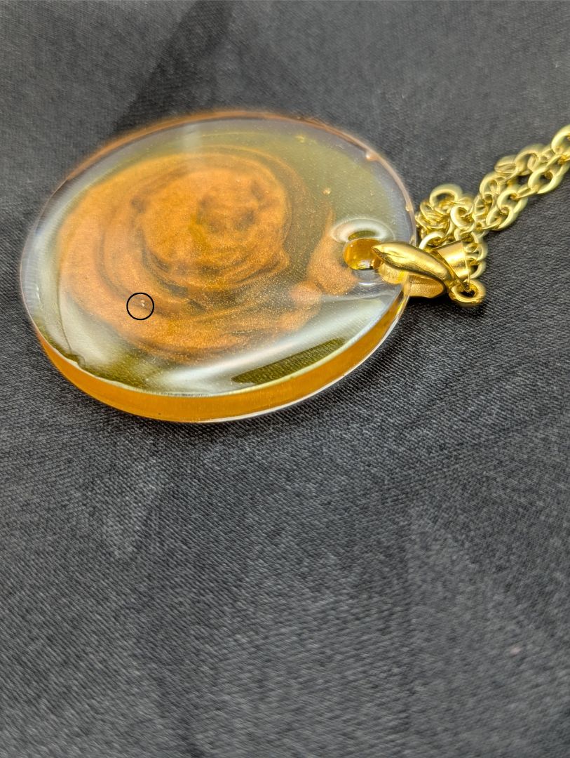 Yellow & orange swirl circle resin pendant on a gold pinch bail & gold plated metal chain.