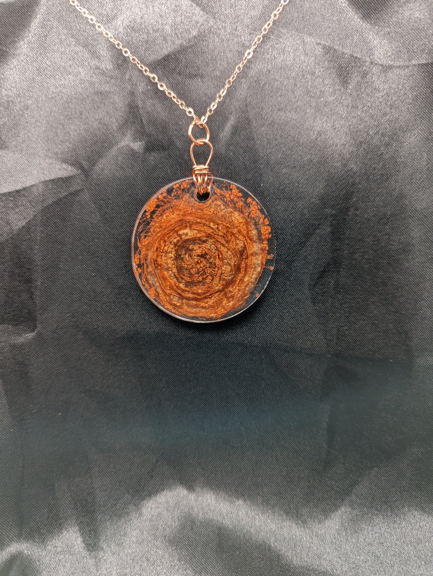 Back view of Wire wrapped copper swirl circle pendant necklace. Resin pendant with a pure copper wire bail on a rose gold colored stainless steel plated metal chain.