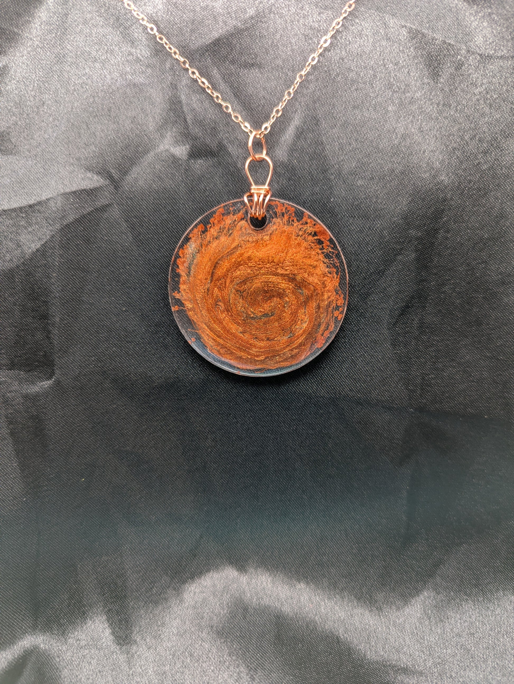 Wire wrapped copper swirl circle pendant necklace. Resin pendant with a pure copper wire bail on a rose gold colored stainless steel plated metal chain.