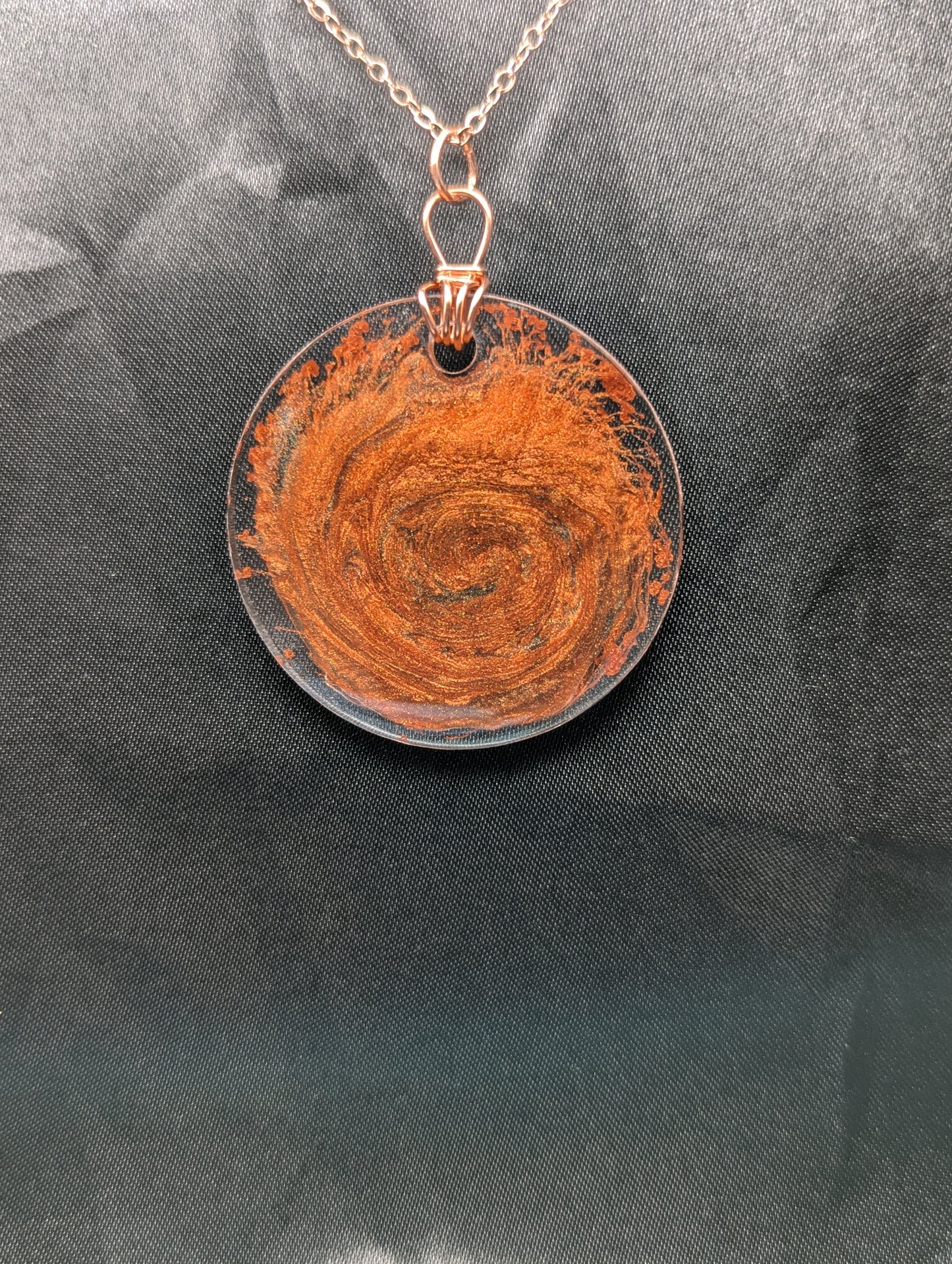 Wire wrapped copper swirl circle pendant necklace. Resin pendant with a pure copper wire bail on a rose gold colored stainless steel plated metal chain.