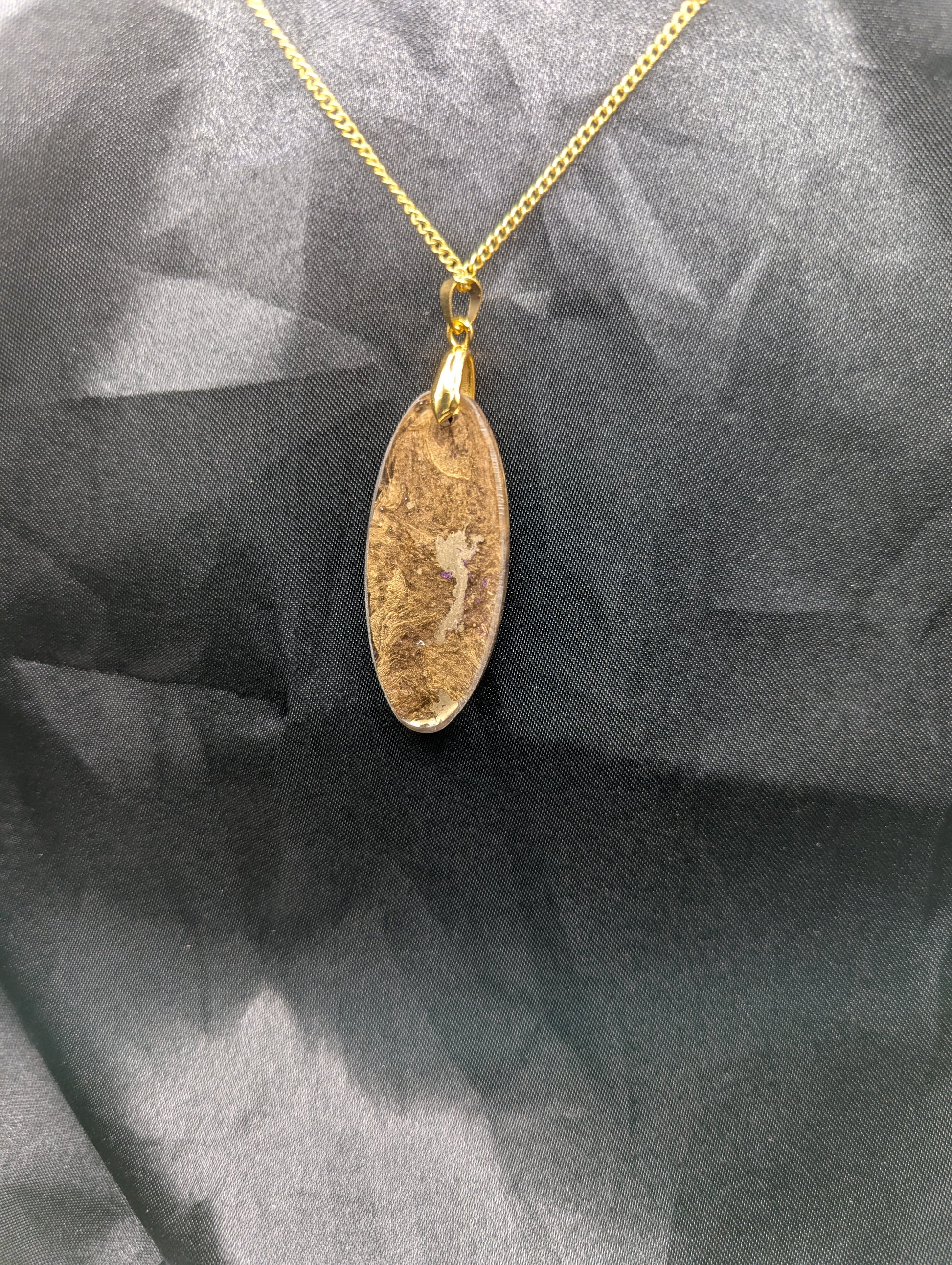 Back view of Rich Gold Swirl with dots of purple Ellipse Resin Pendant on a gold pinch bail and a gold plated metal chain.