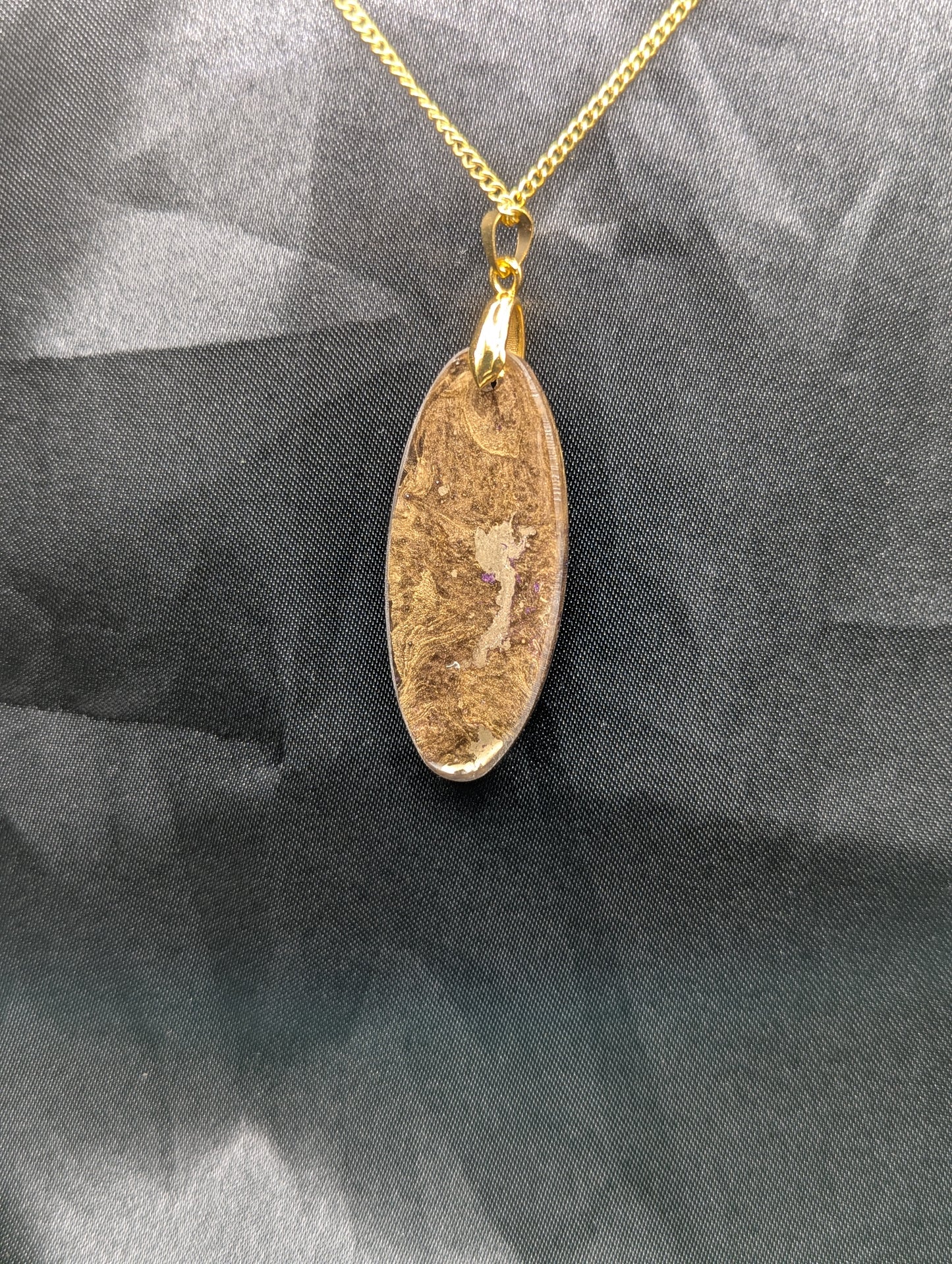 Back view of Rich Gold Swirl with dots of purple Ellipse Resin Pendant on a gold pinch bail and a gold plated metal chain.