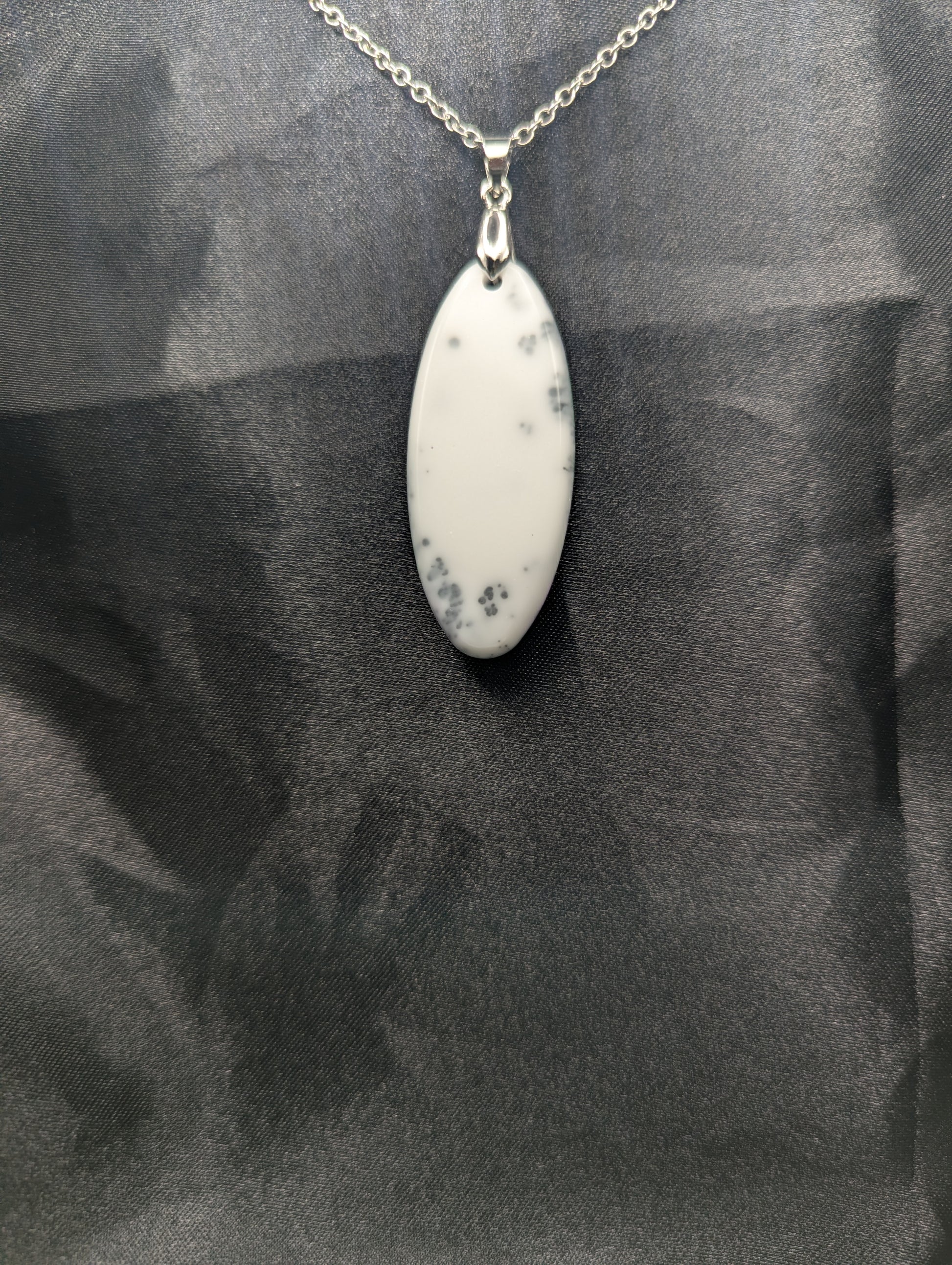 Back view of Black swirl ellipse resin pendant necklace with a white background. Resin necklace on a silver pinch bail & stainless steel chain.