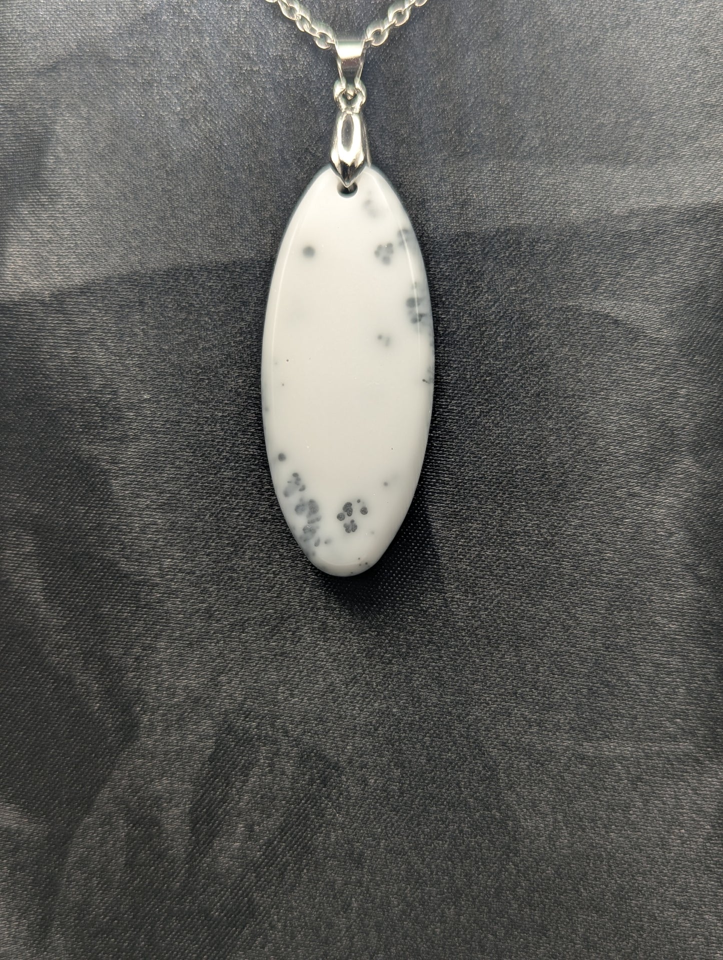 Back view of Black swirl ellipse resin pendant necklace with a white background. Resin necklace on a silver pinch bail & stainless steel chain.