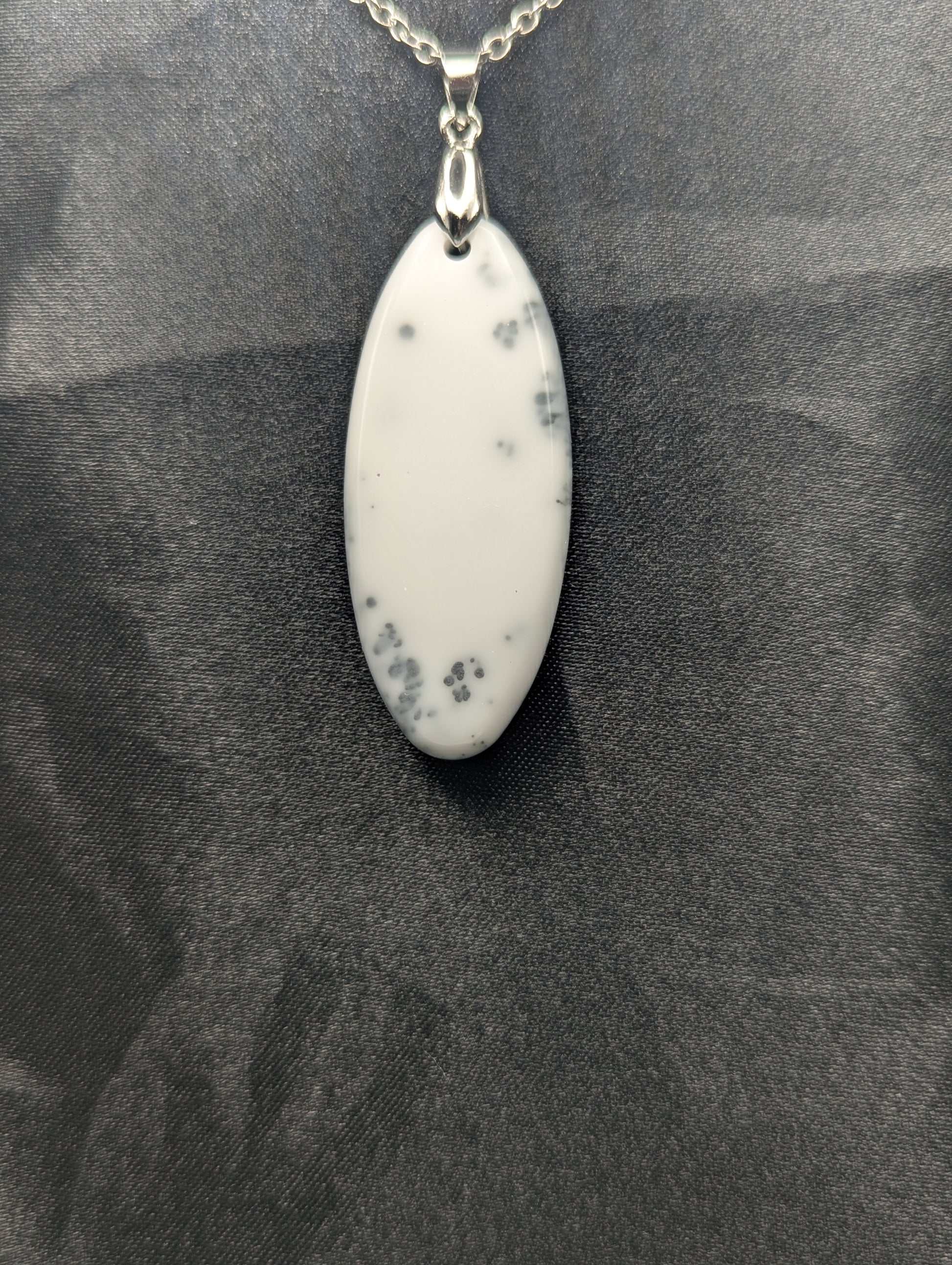 Back view of Black swirl ellipse resin pendant necklace with a white background. Resin necklace on a silver pinch bail & stainless steel chain.