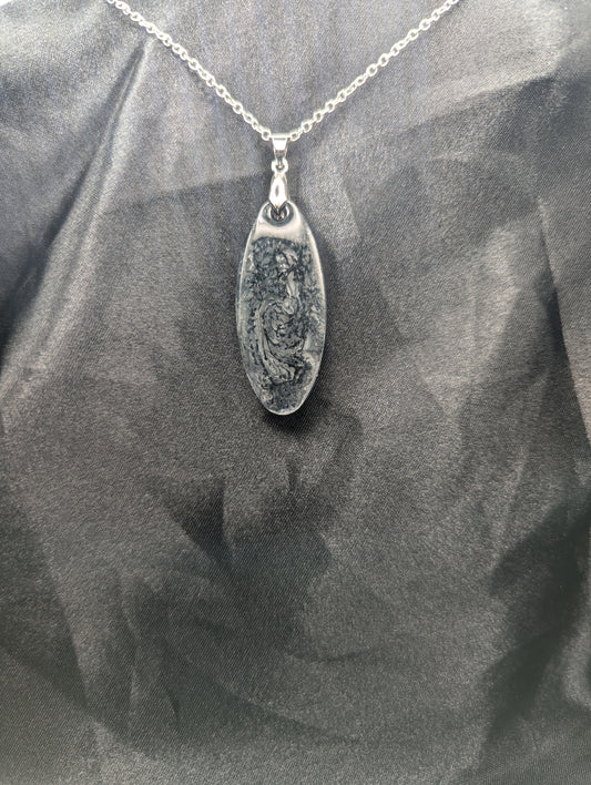 Black swirl ellipse resin pendant necklace with a white background. Resin necklace on a silver pinch bail & stainless steel chain.