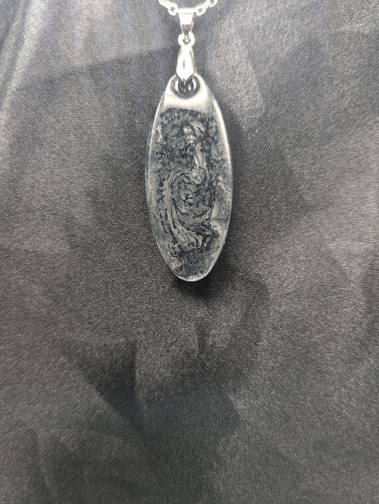 Black swirl ellipse resin pendant necklace with a white background. Resin necklace on a silver pinch bail & stainless steel chain.