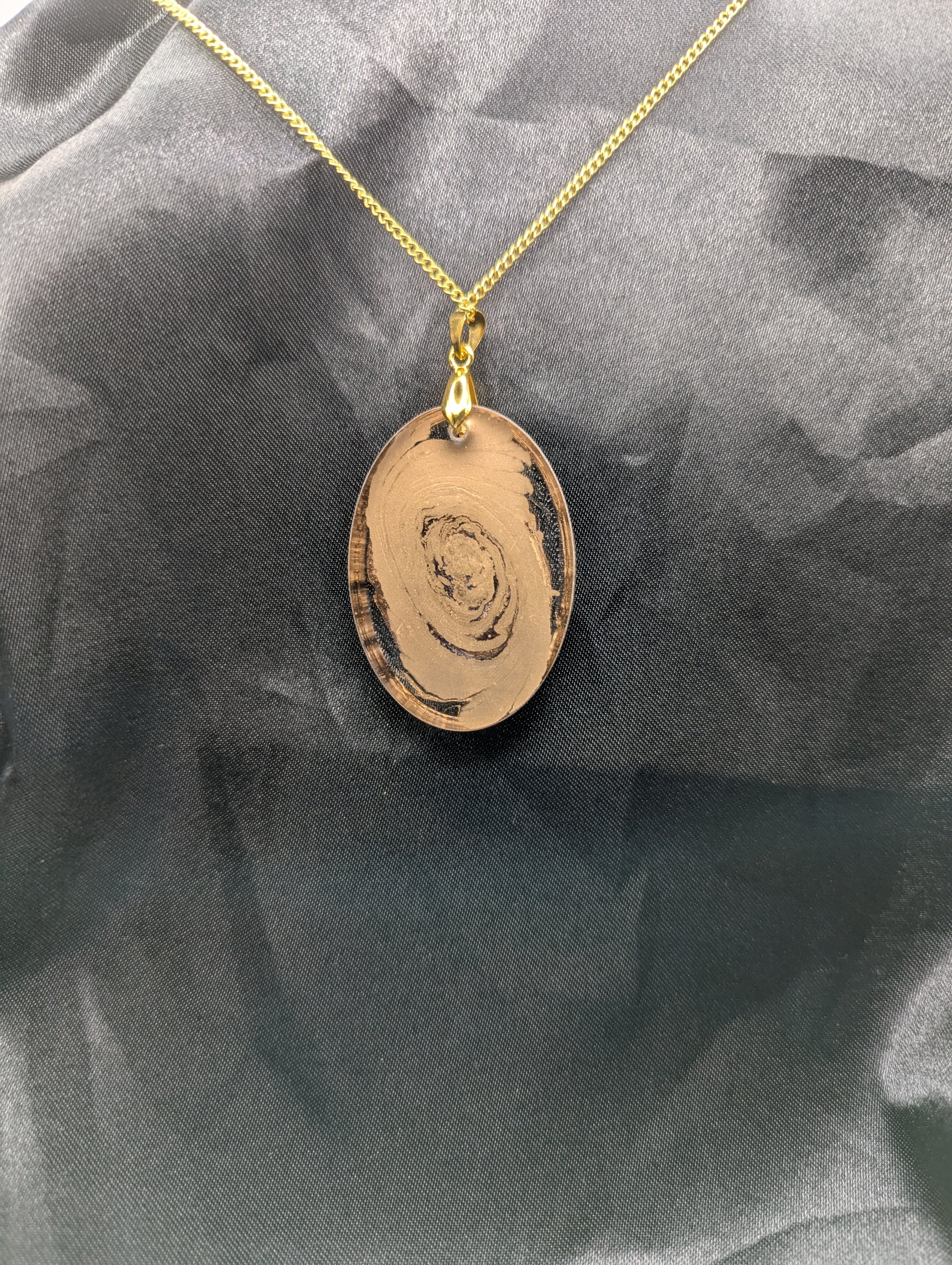 Back view of Rich Gold Swirl Resin Oval Pendant on a gold pinch bail and a gold plated metal chain.