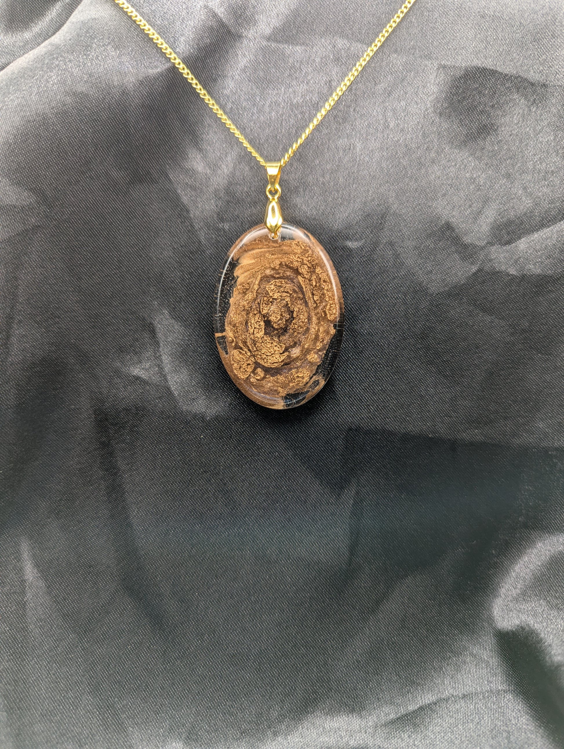 Rich Gold Swirl Resin Oval Pendant on a gold pinch bail and a gold plated metal chain.