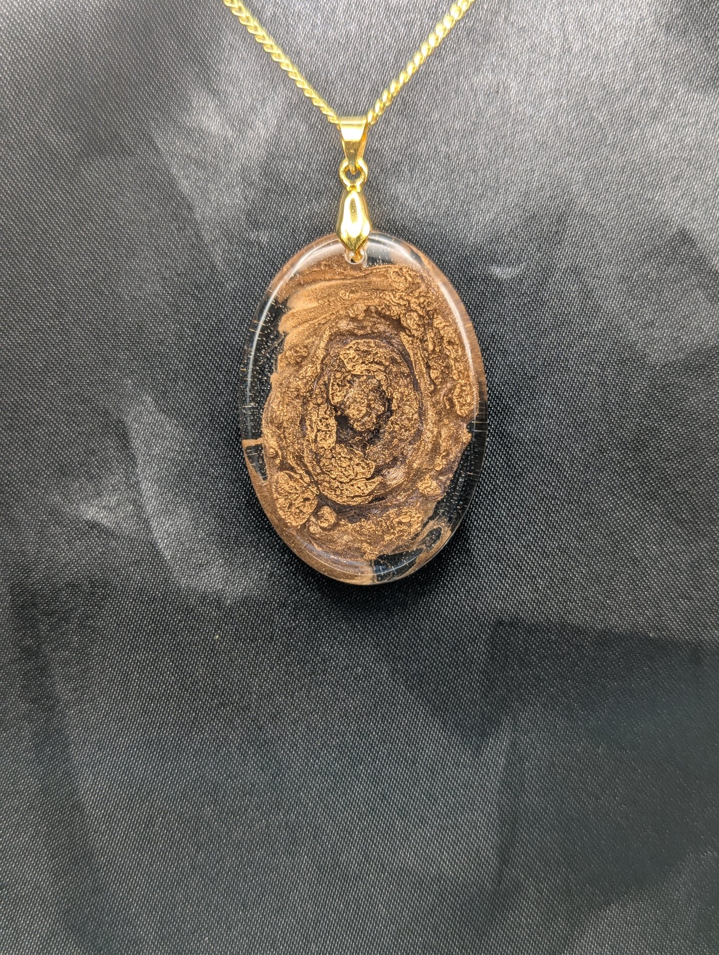 Rich Gold Swirl Resin Oval Pendant on a gold pinch bail and a gold plated metal chain.