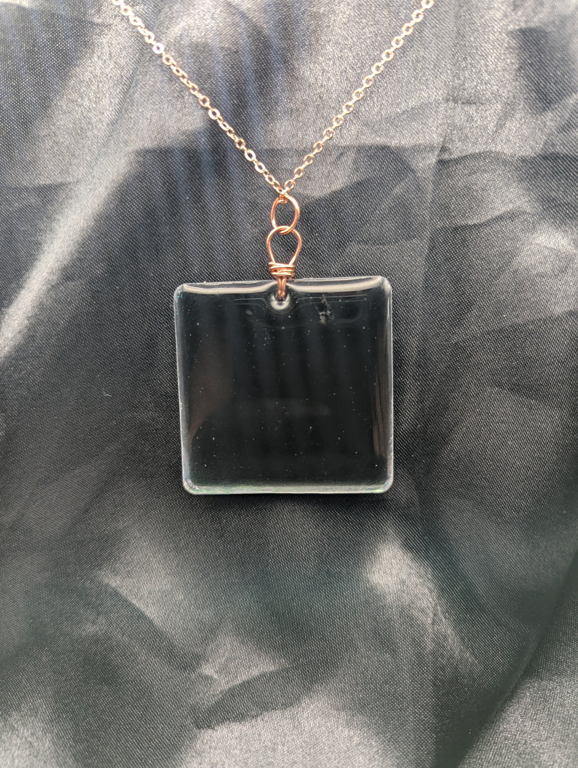 Back view of Blue square resin pendant with a color shift background. Resin pendant necklace on a pure copper wire wrapped bail & rose gold colored stainless steel plated metal chain.