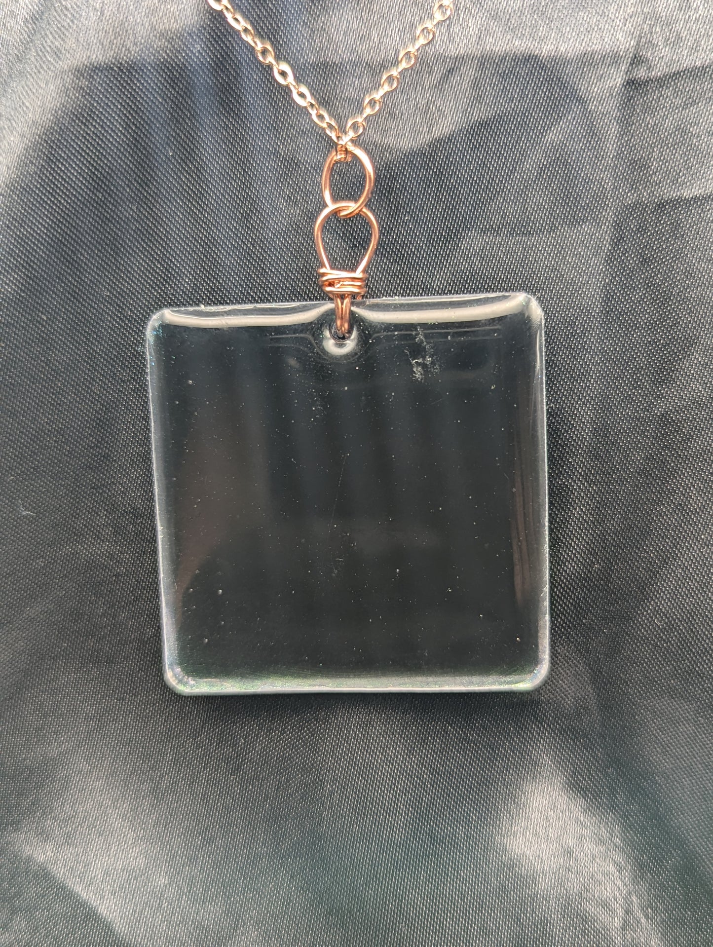 Back view of Blue square resin pendant with a color shift background. Resin pendant necklace on a pure copper wire wrapped bail & rose gold colored stainless steel plated metal chain.