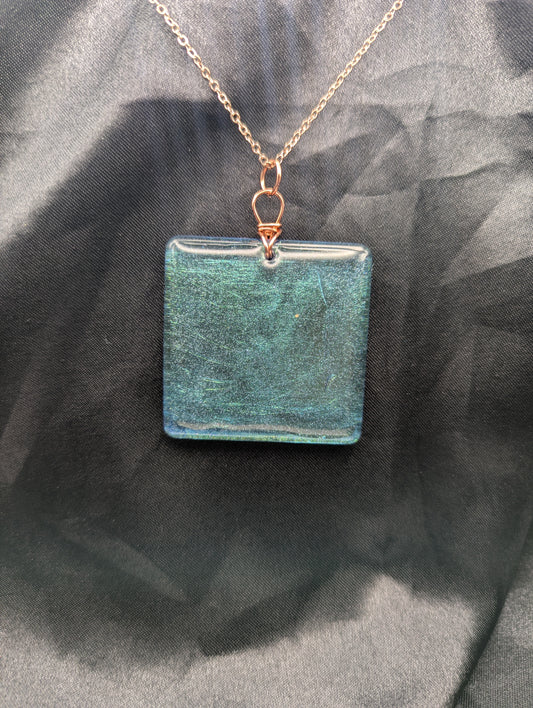 Blue square resin pendant with a color shift background. Resin pendant necklace on a pure copper wire wrapped bail & rose gold colored stainless steel plated metal chain.