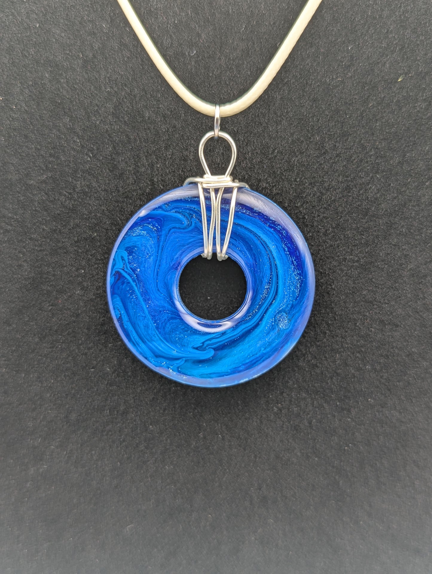 Back view of Wire Wrapped Donut Resin Pendant Necklace - Petri Effect with shades of blue. Resin Necklace on a waxed cotton cord.