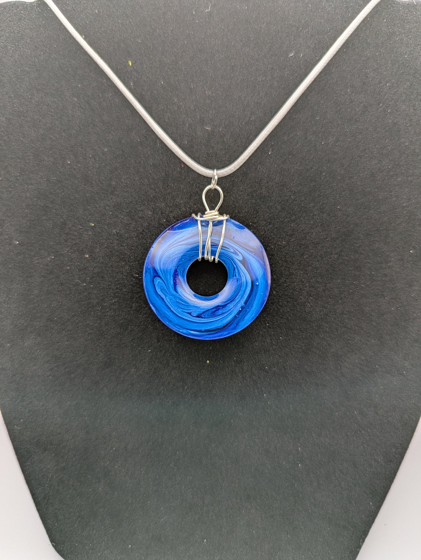 Back view of Wire Wrapped Donut Resin Pendant Necklace - Petri Effect with shades of blue swirls. Resin Necklace on a waxed cotton cord.