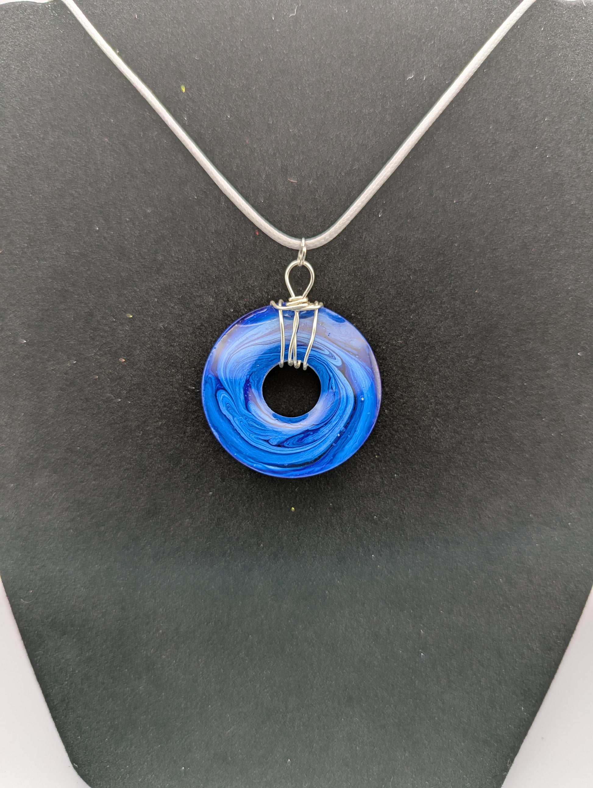 Back view of Wire Wrapped Donut Resin Pendant Necklace - Petri Effect with shades of blue swirls. Resin Necklace on a waxed cotton cord.