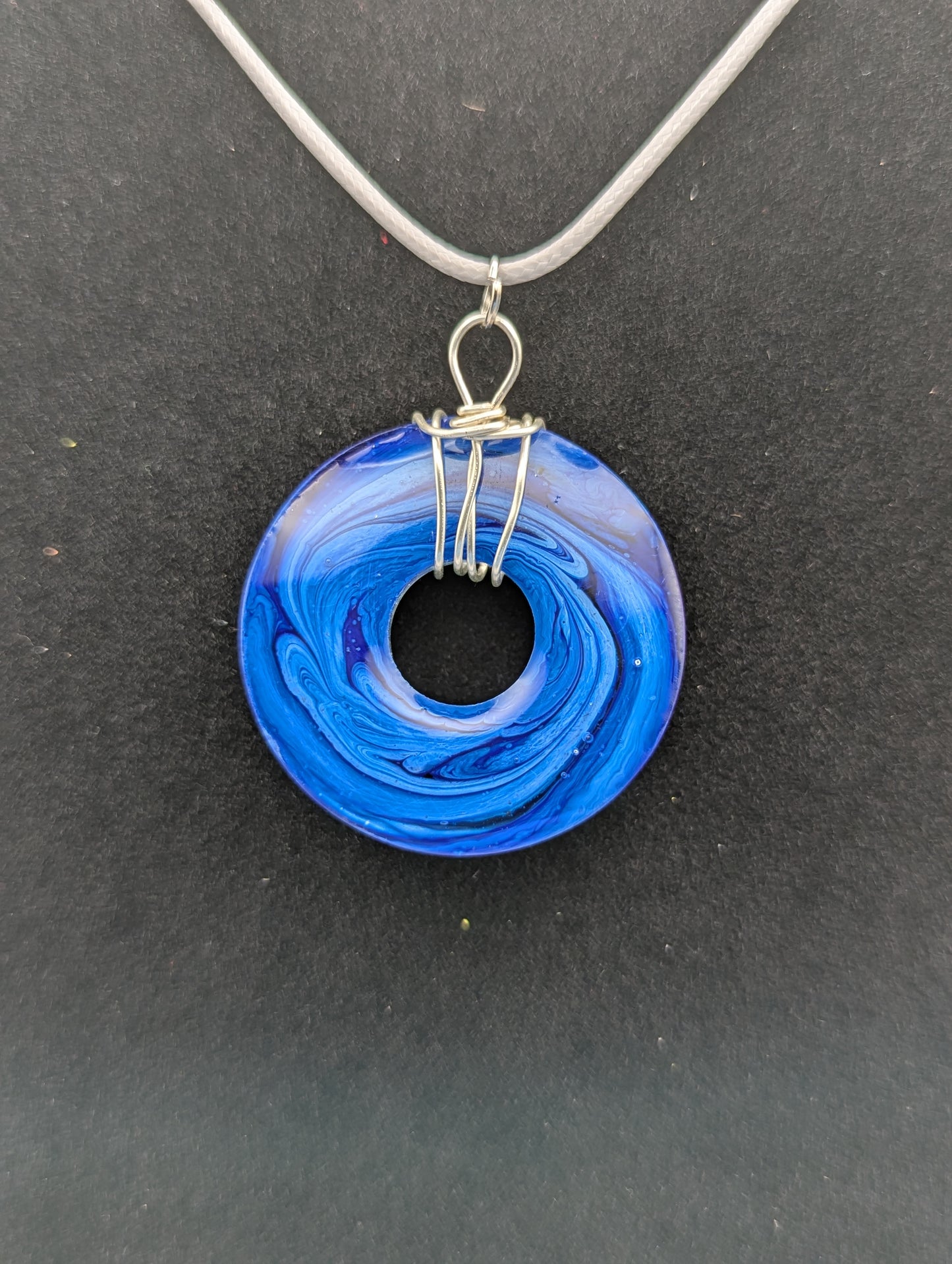 Back view of Wire Wrapped Donut Resin Pendant Necklace - Petri Effect with shades of blue swirls. Resin Necklace on a waxed cotton cord.