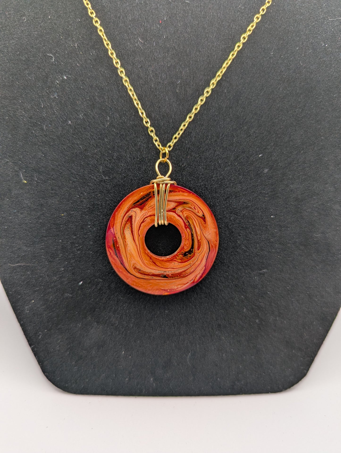 Back view of Wire Wrapped Donut Resin Pendant Necklace - Petri Effect with shades of orange & red swirls. Resin Necklace on a gold plated chain.